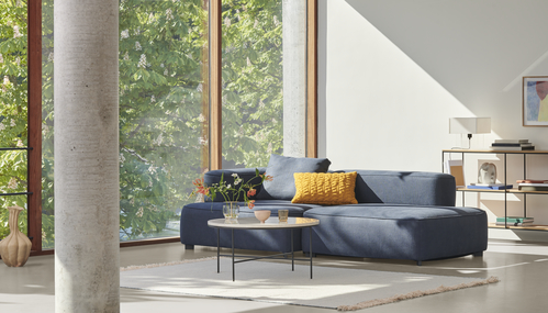 Wohnzimmer mit blauem Sofa, Tisch und Fritz Hansen Planner Regal zur Aufbewahrung von Büchern.