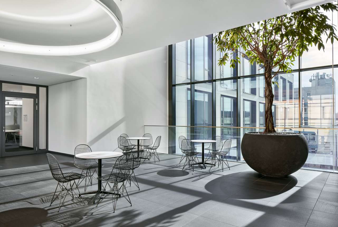 Heller Raum mit mehreren Vitra Bistro Tischen, runden Tischen und schwarzen Stühlen.