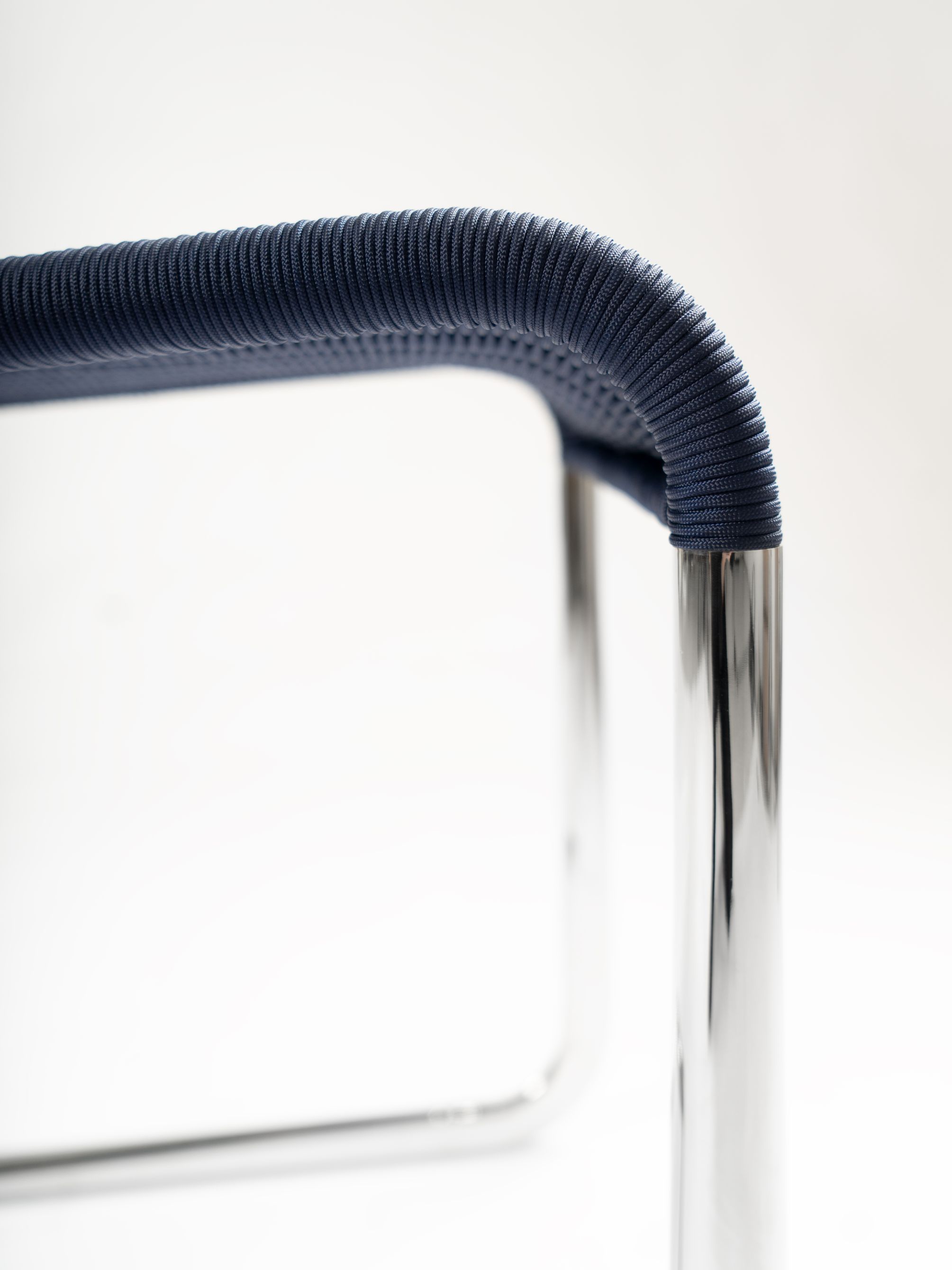 Detailaufnahme: Dunkelblauer B25 Kragstuhl von Tecta mit verchromtem Stahlrohr Gestell. Designklassiker für modernes Wohnen.
