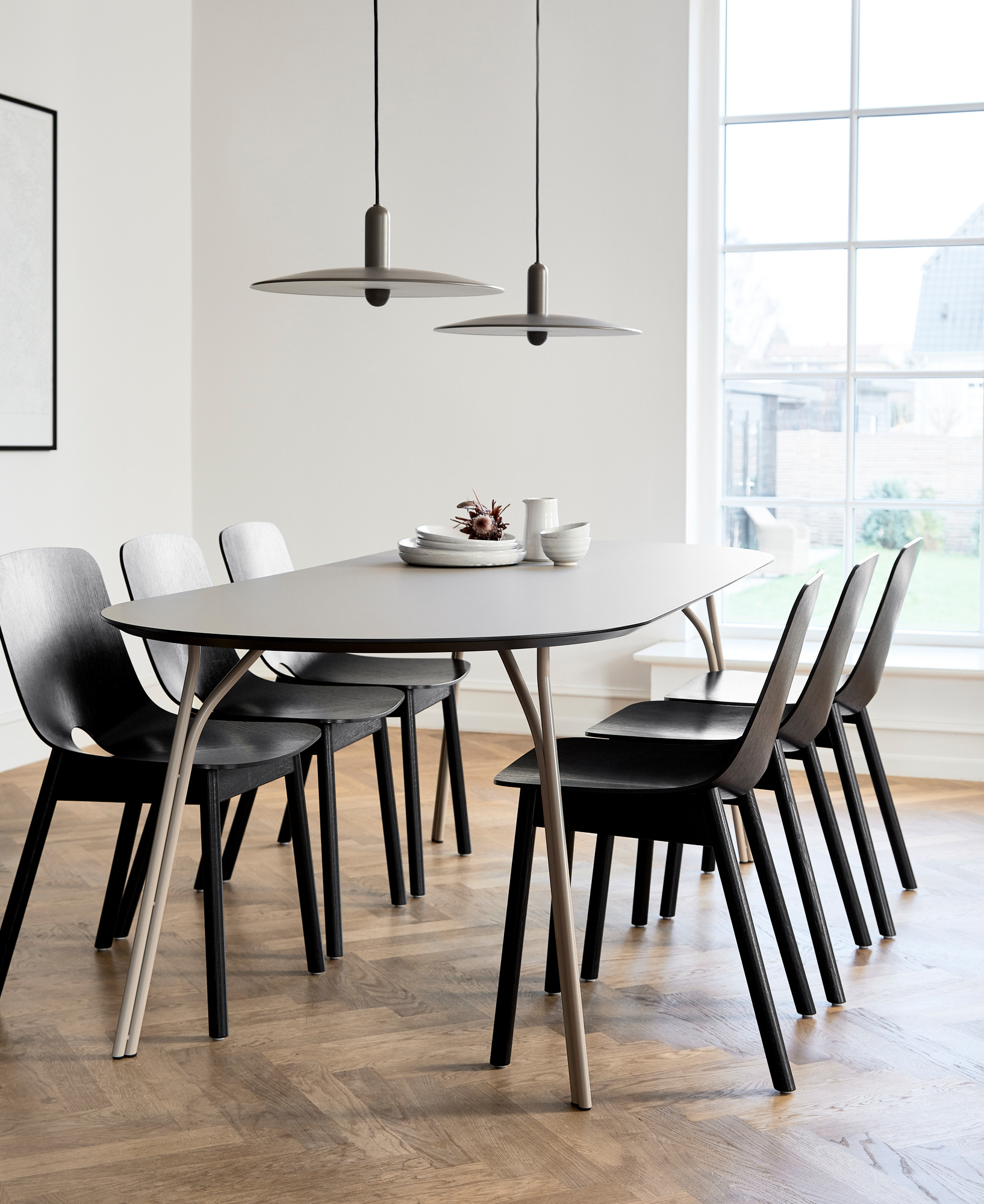 Eleganter Woud Tree Esstisch 90x220 mit sechs schwarzen Stühlen und stilvollen Pendelleuchten im hellen Esszimmer.