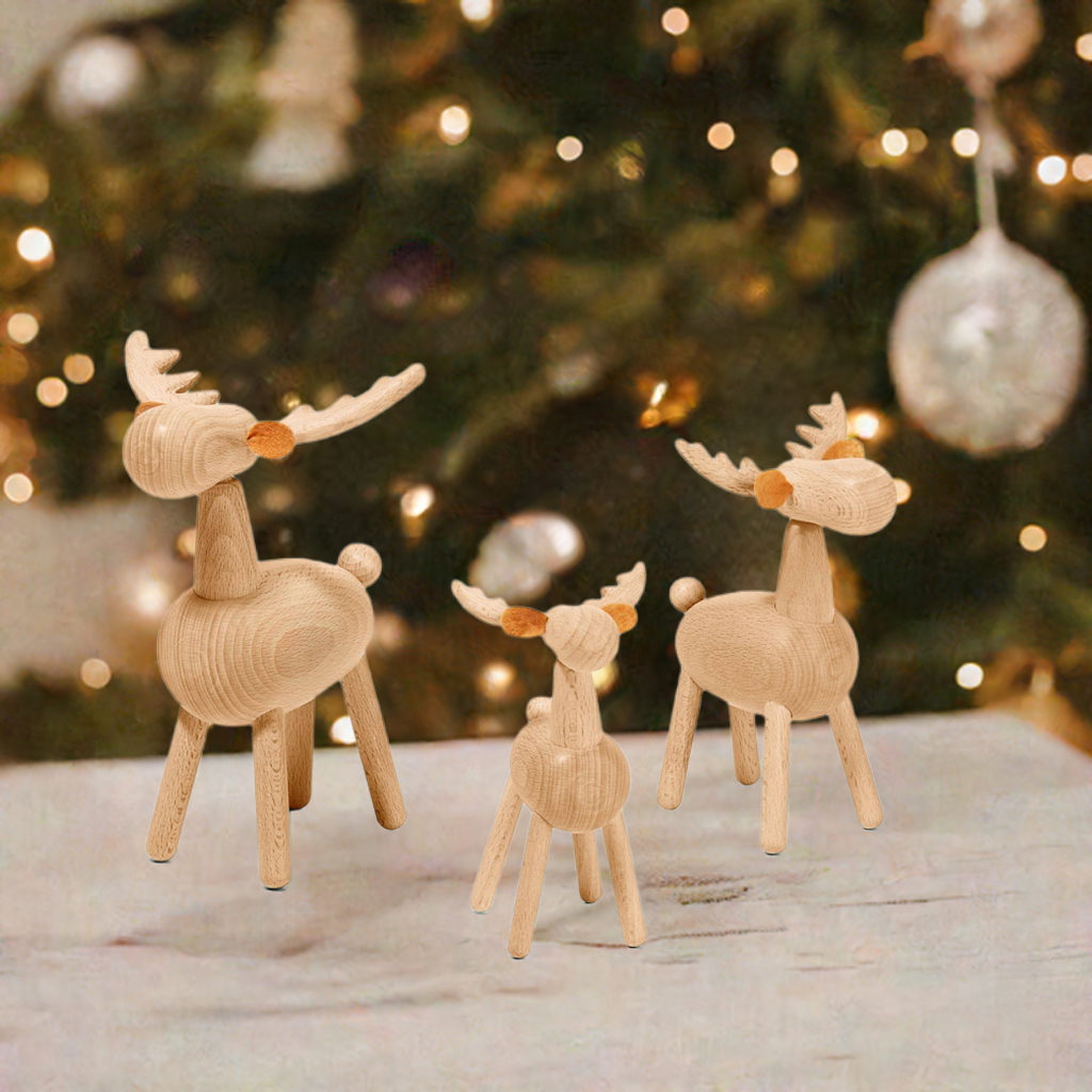 Drei Elmar Holz Elche von Philippi, handgefertigte Holzfiguren als Weihnachtsdekoration vor einem Weihnachtsbaum.