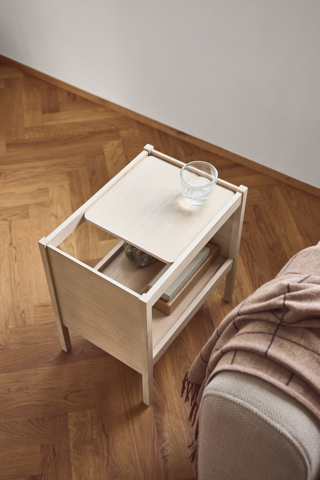 Journal Beistelltisch von Form & Refine aus hellem Holz mit Glas Wasser und Ablage.