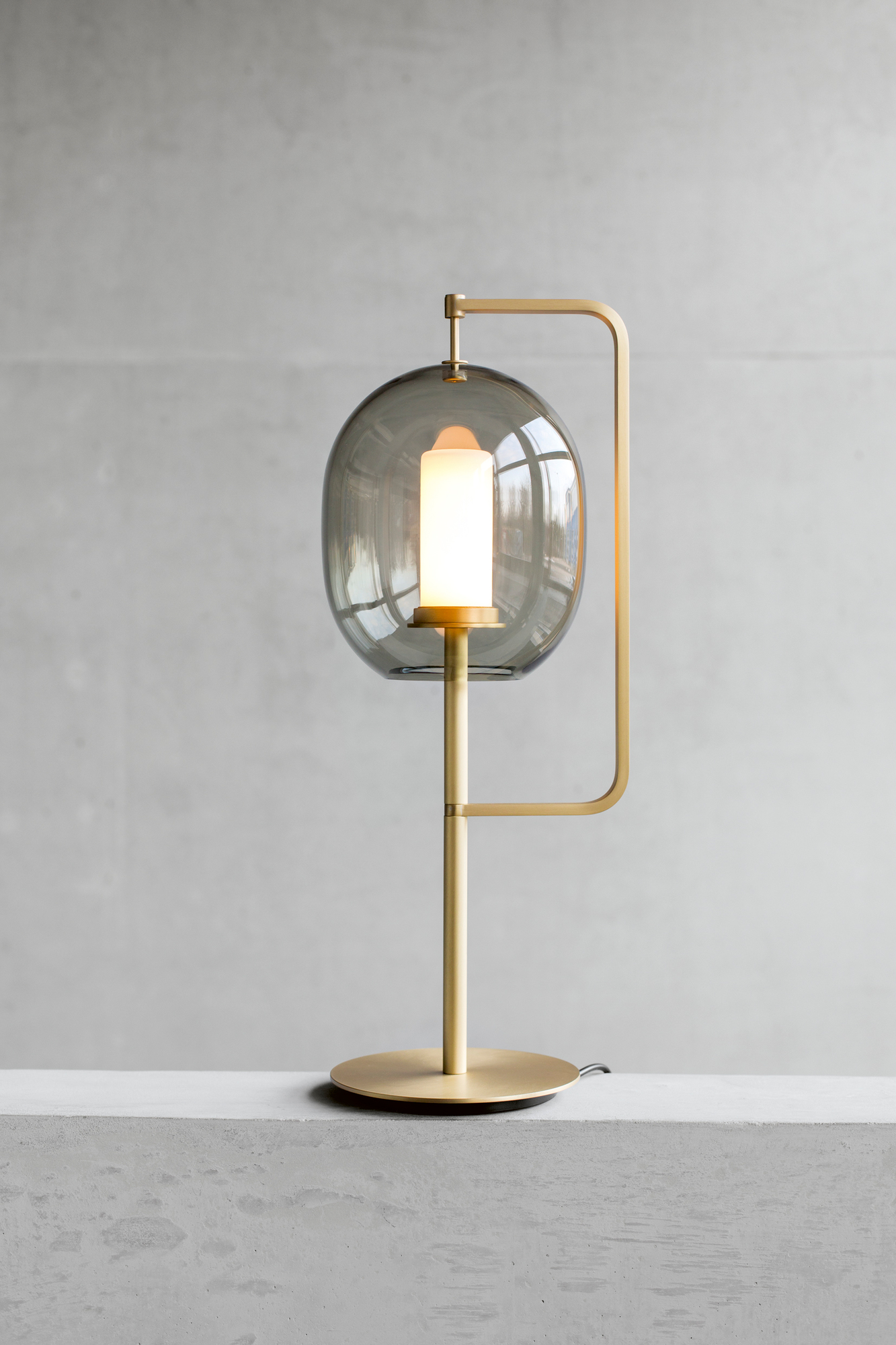 Lantern Light Tischleuchte Messing ClassiCon: Moderne Tischlampe mit grauem Glasschirm und Messinggestell.