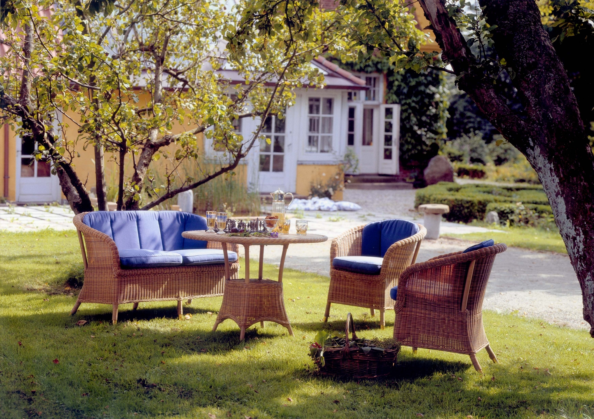 Derby Cane-Line Sessel und Sofa aus Rattan mit blauen Polstern im Garten.