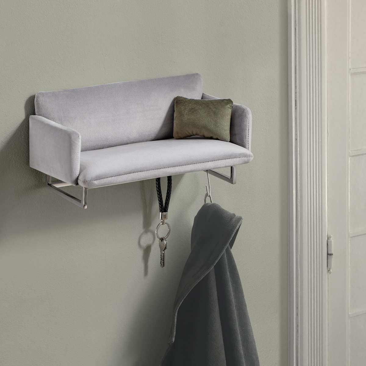 Graue Mini-Garderobe im Sofa-Design von Philippi mit Schlüssel und Jacke an der Wand.