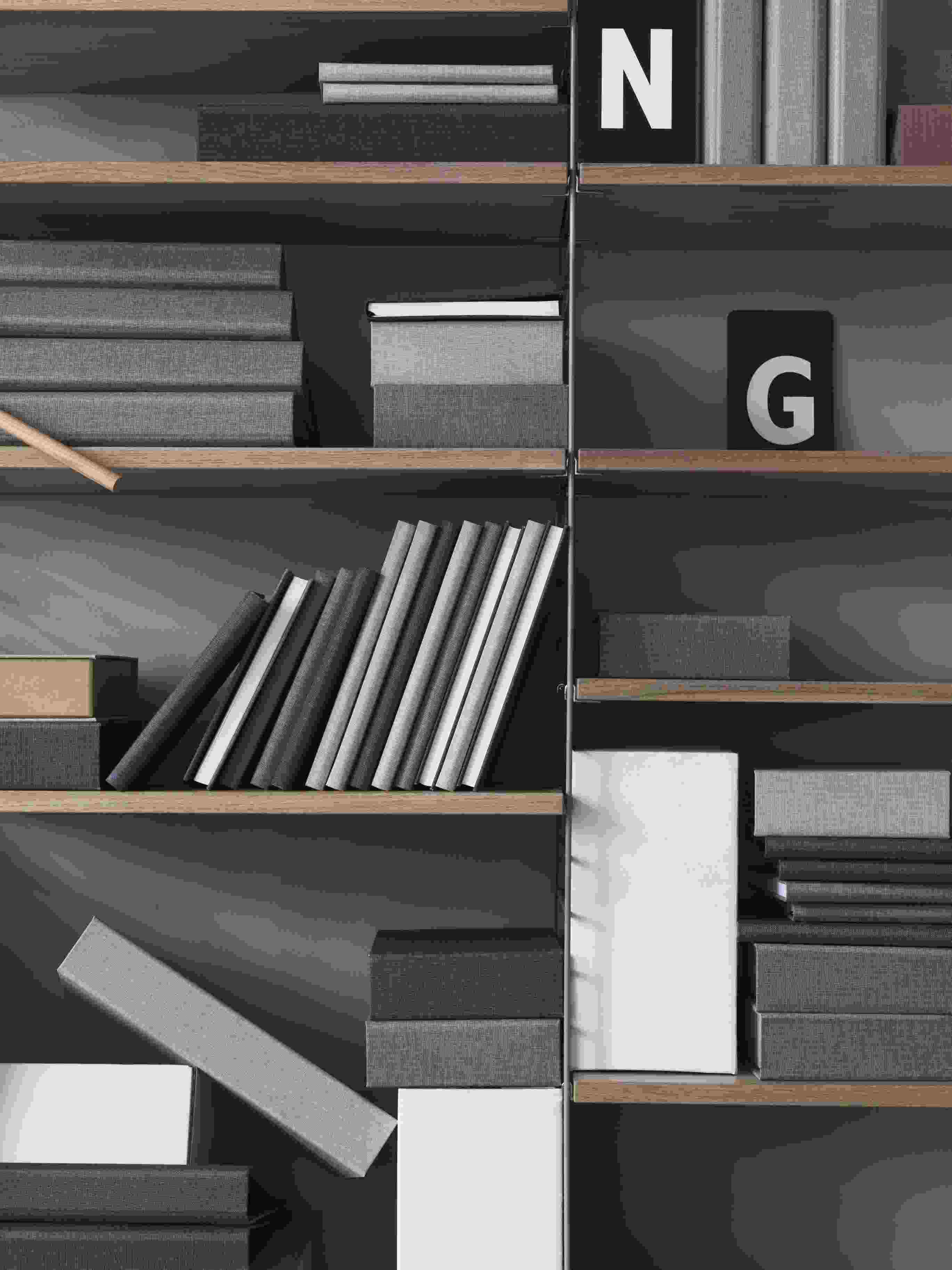 Detailaufnahme eines String Regalsystems in Grau mit Büchern und dekorativen Boxen.