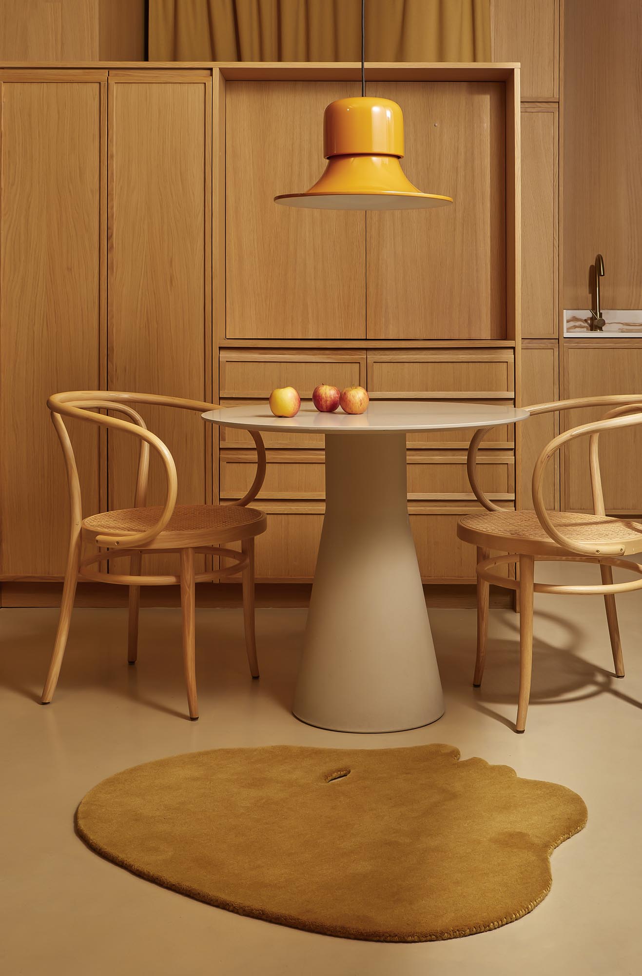 Nanimarquina Teppich Talk Talk in Blaugrün unter Esstisch mit Stühlen und gelber Lampe im modernen Interieur.