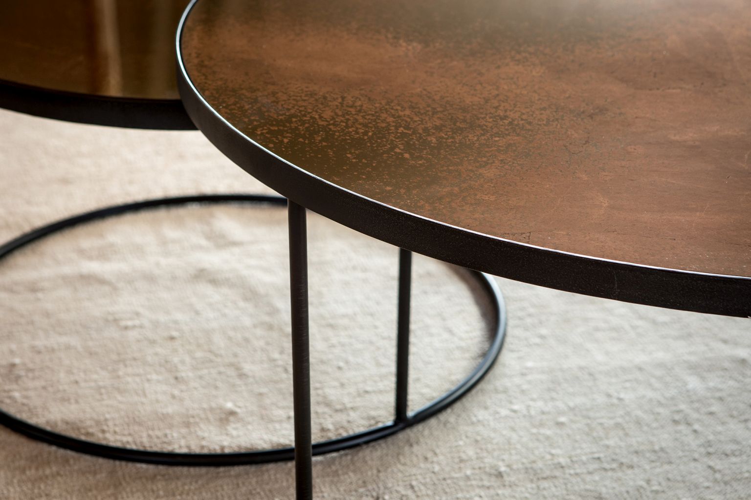 Detailaufnahme: Nesting Couchtisch 2er Set von Ethnicraft, bronze Tischplatten, schwarzes Metallgestell.