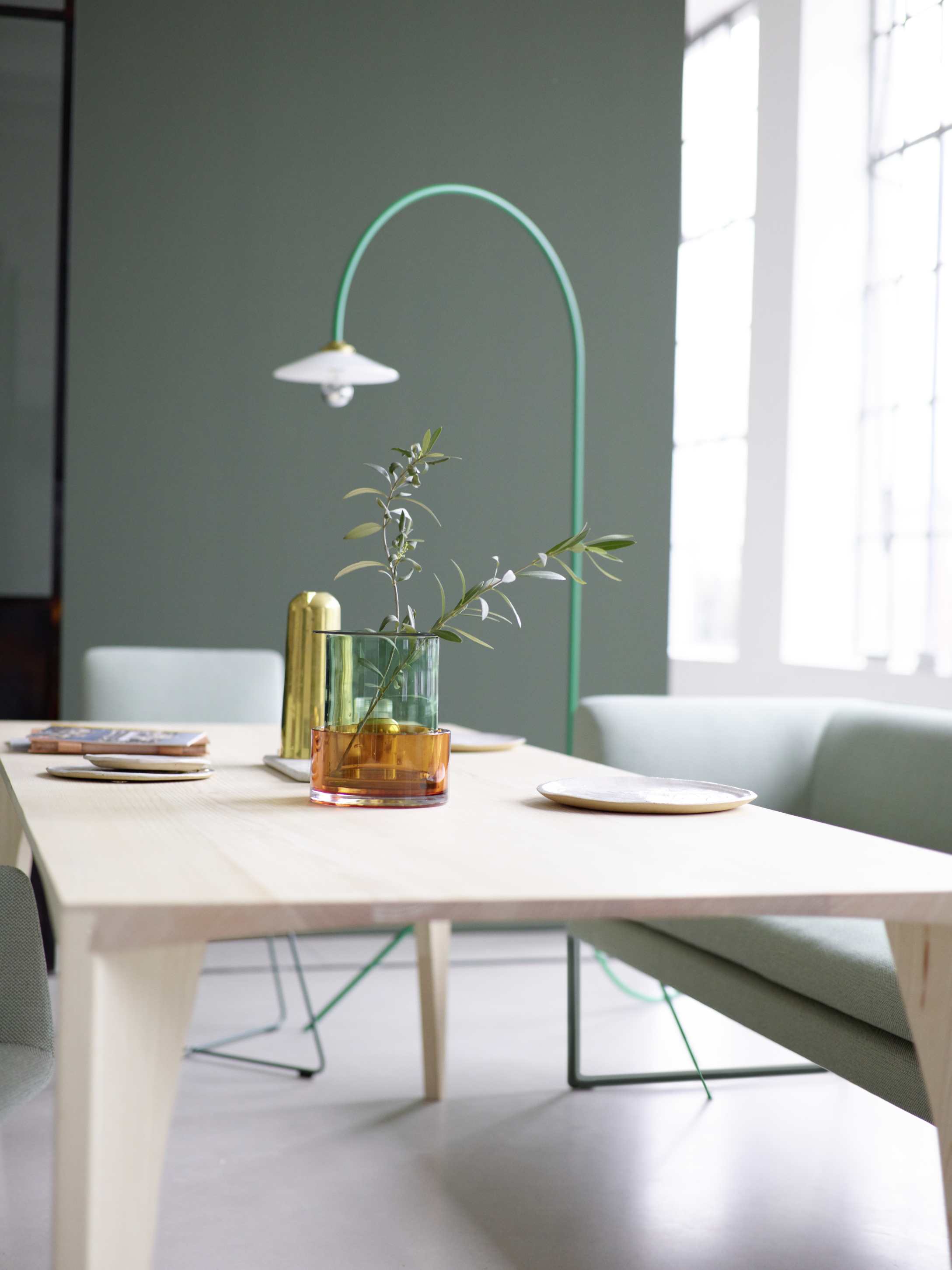 Delta Tisch von Cor, Esstisch aus hellem Holz mit Vasen und Geschirr dekoriert.