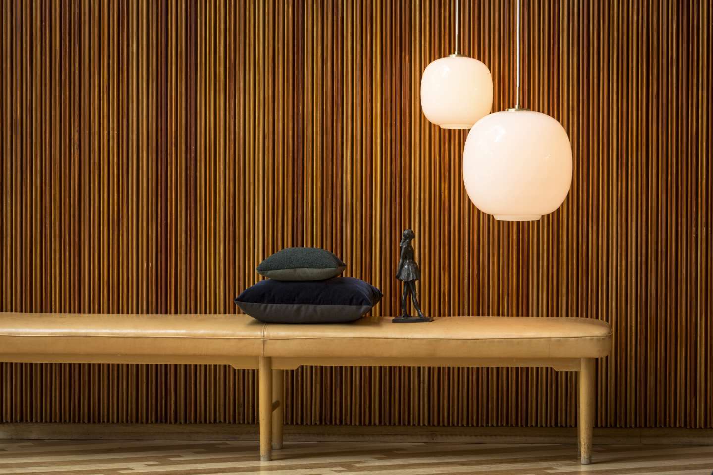 Zwei VL45 Radiohus Pendelleuchten von Louis Poulsen über einer Bank mit Kissen und Dekoration.