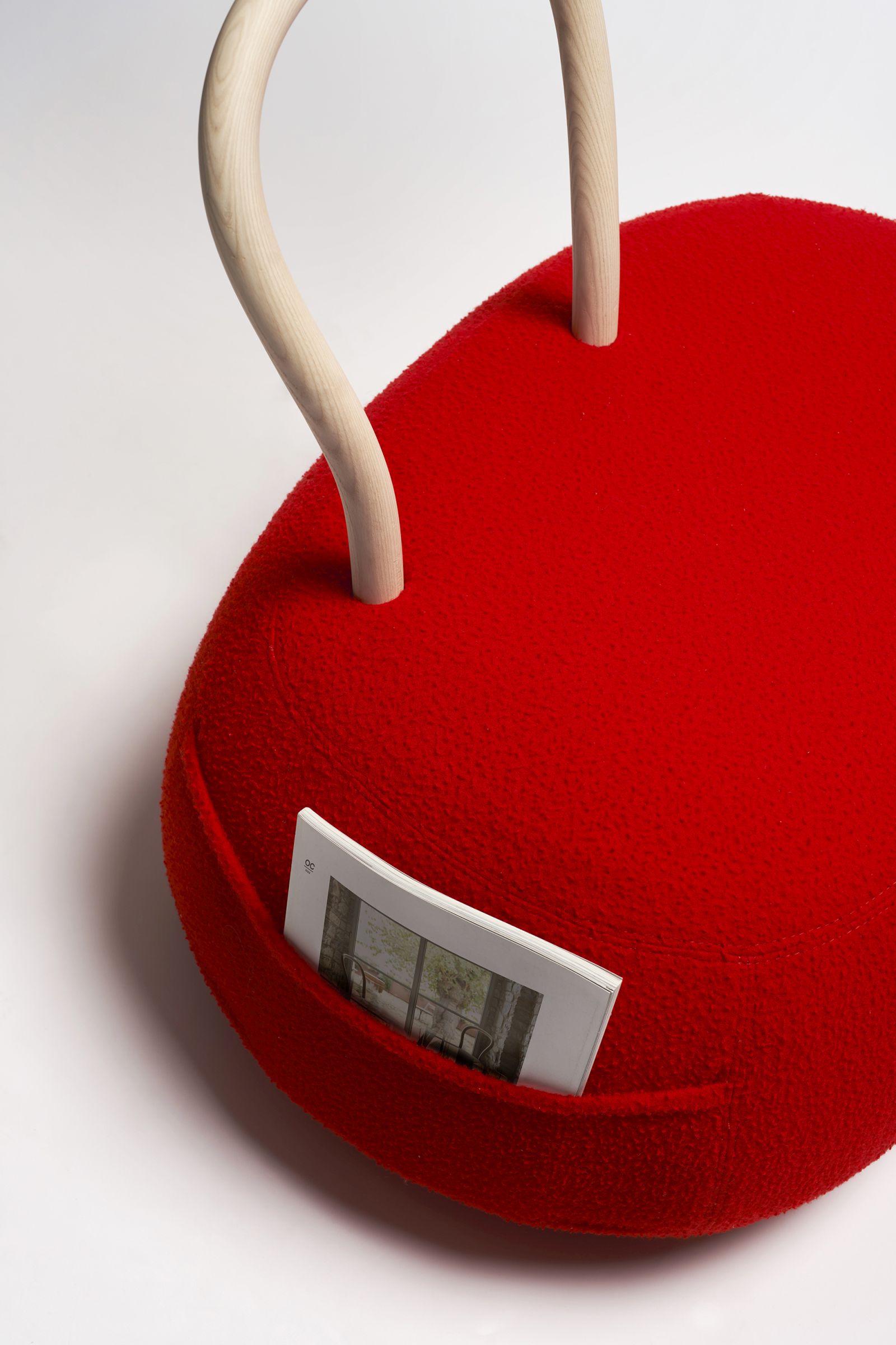 Detailaufnahme des roten Yum Yum Sessels von Opinion Ciatti mit Magazin in der Seitentasche.