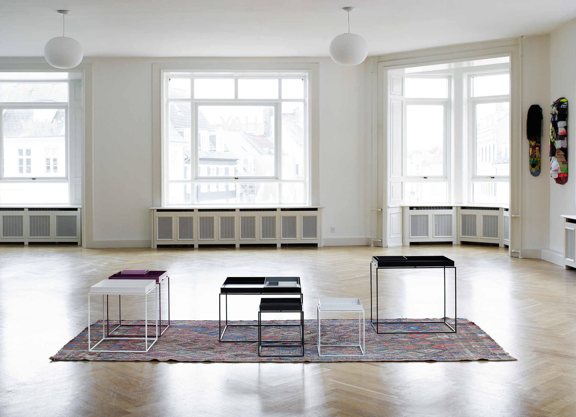 Helle Raumansicht mit vier Tray Table S Tischen von Hay in Schwarz, Weiß und Lila.