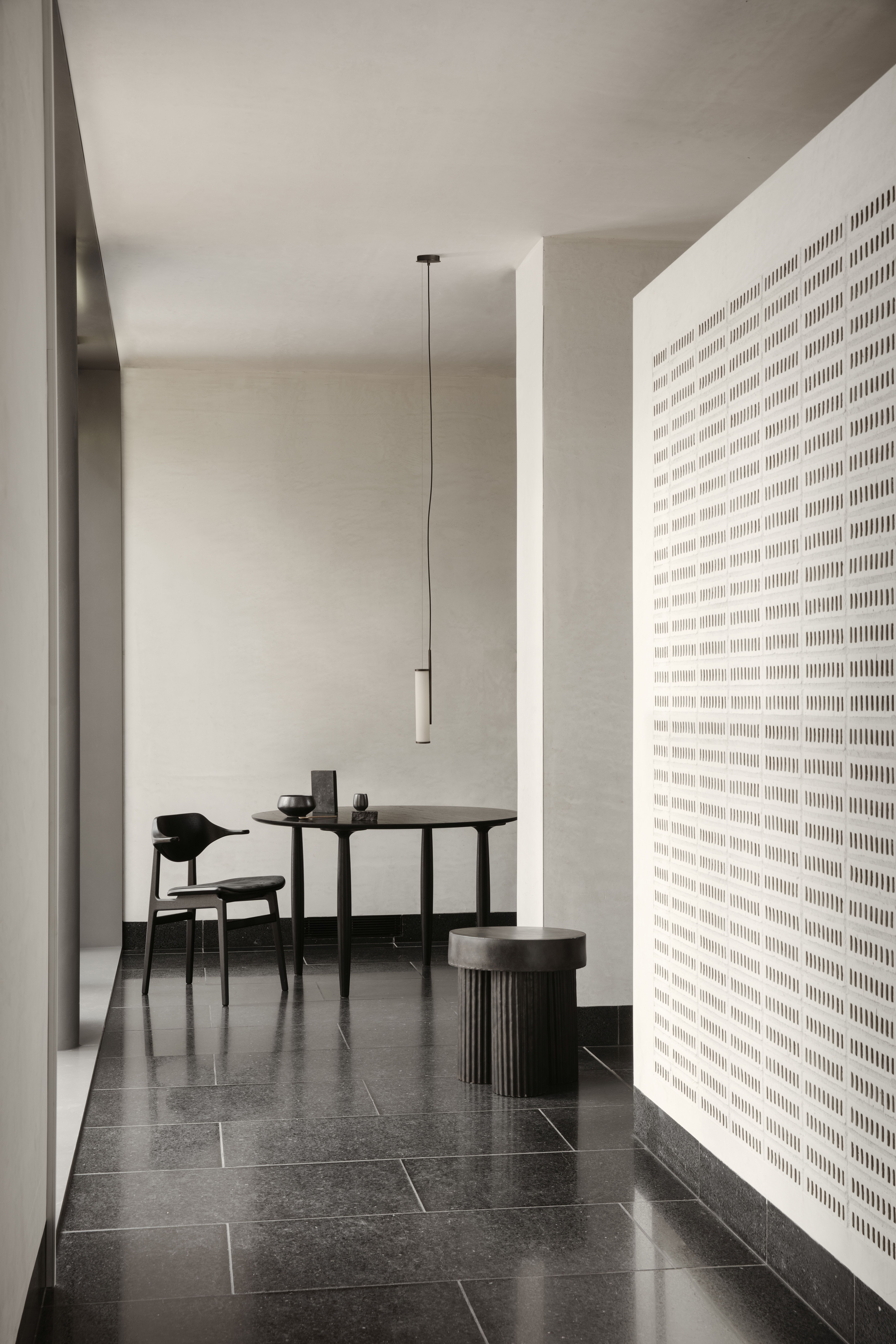 Oku Esstisch rund Eiche schwarz Norr11 mit Stuhl und Hocker in minimalistischem Interieur.