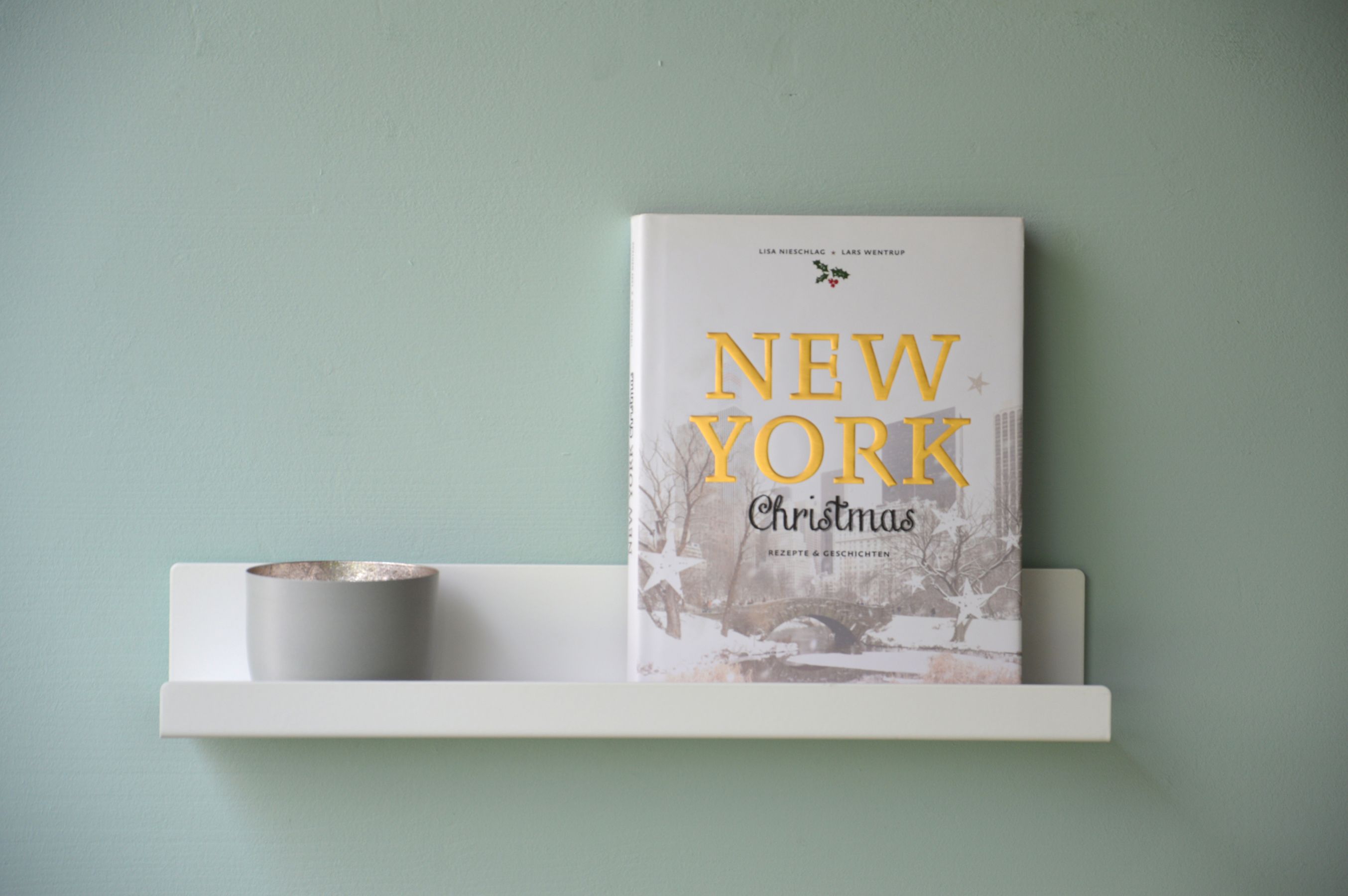 Schwarzes Jill Wandregal von Jan Kurtz (80 cm) an Wand mit Buch und Deko.