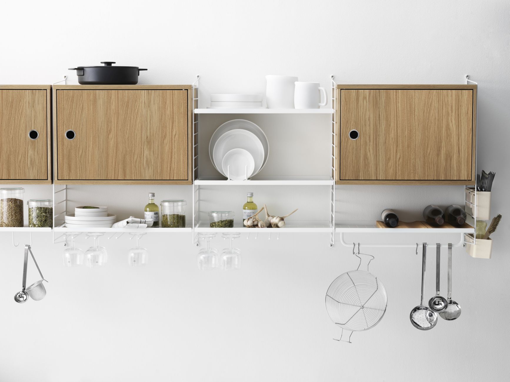 Detailaufnahme eines String Regalsystems mit Metallboden und Küchenutensilien.