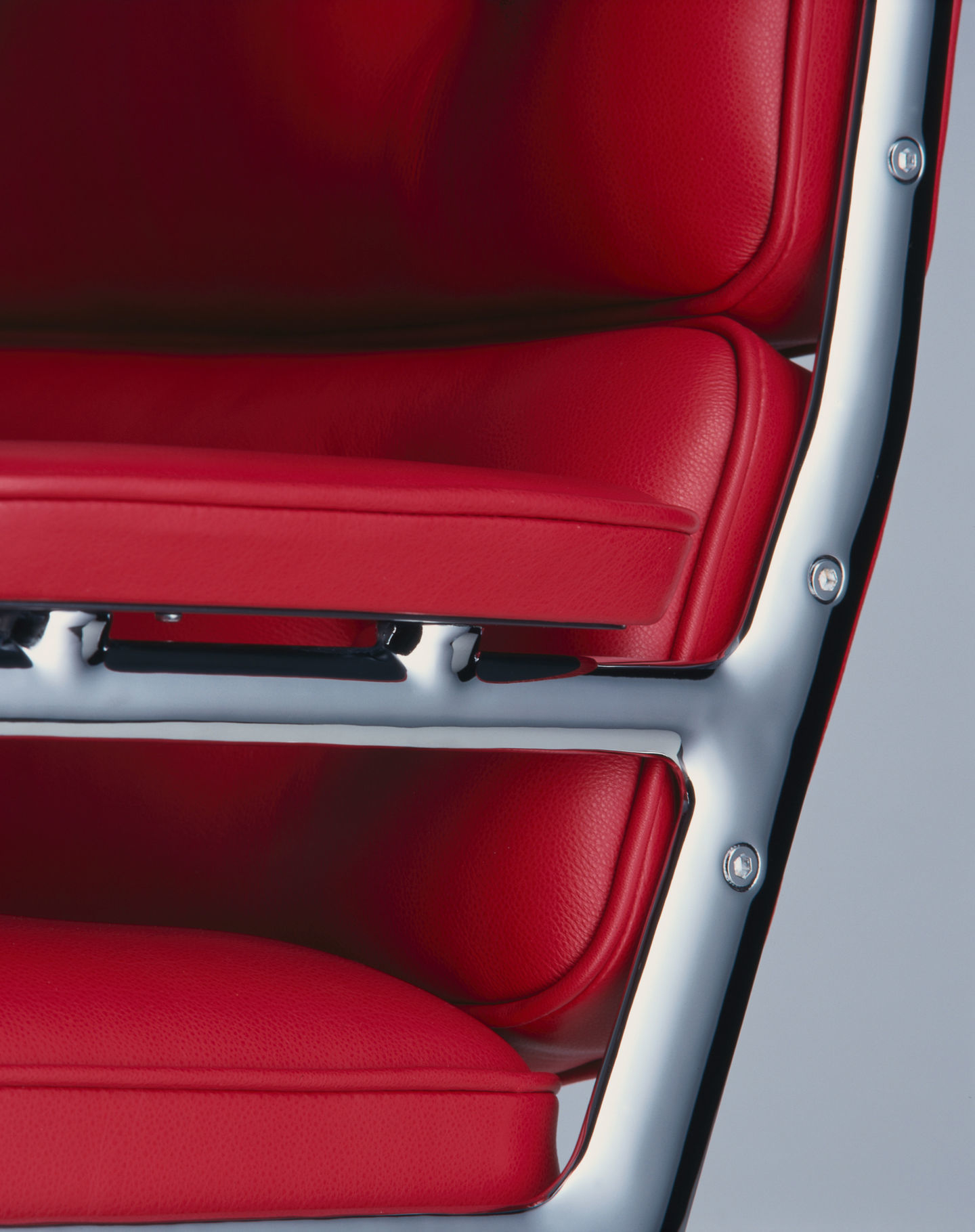 Detailaufnahme: Roter Lederbezug und verchromtes Gestell des Vitra Lobby Chair ES104 Stuhls.