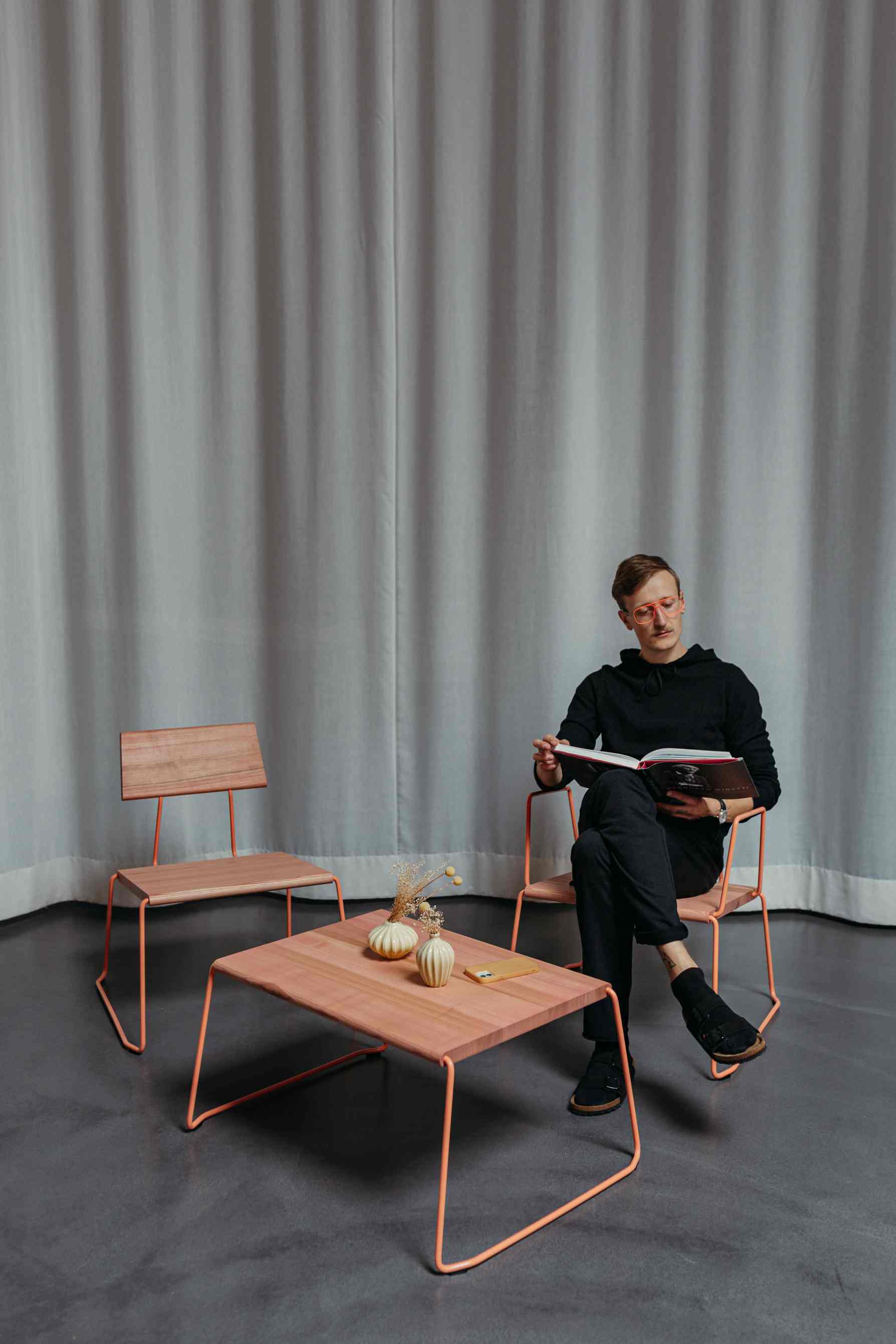 Mann liest am D:009 Coffeetable von Fuchs & Habicht. Moderner Couchtisch mit Holzplatte.