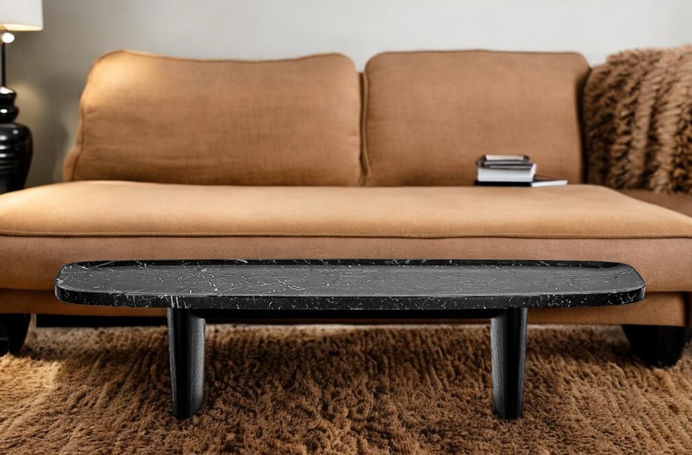 Matéria Couchtisch von Classicon, Nero Marquina Marmor, vor einem braunen Sofa auf Teppich.