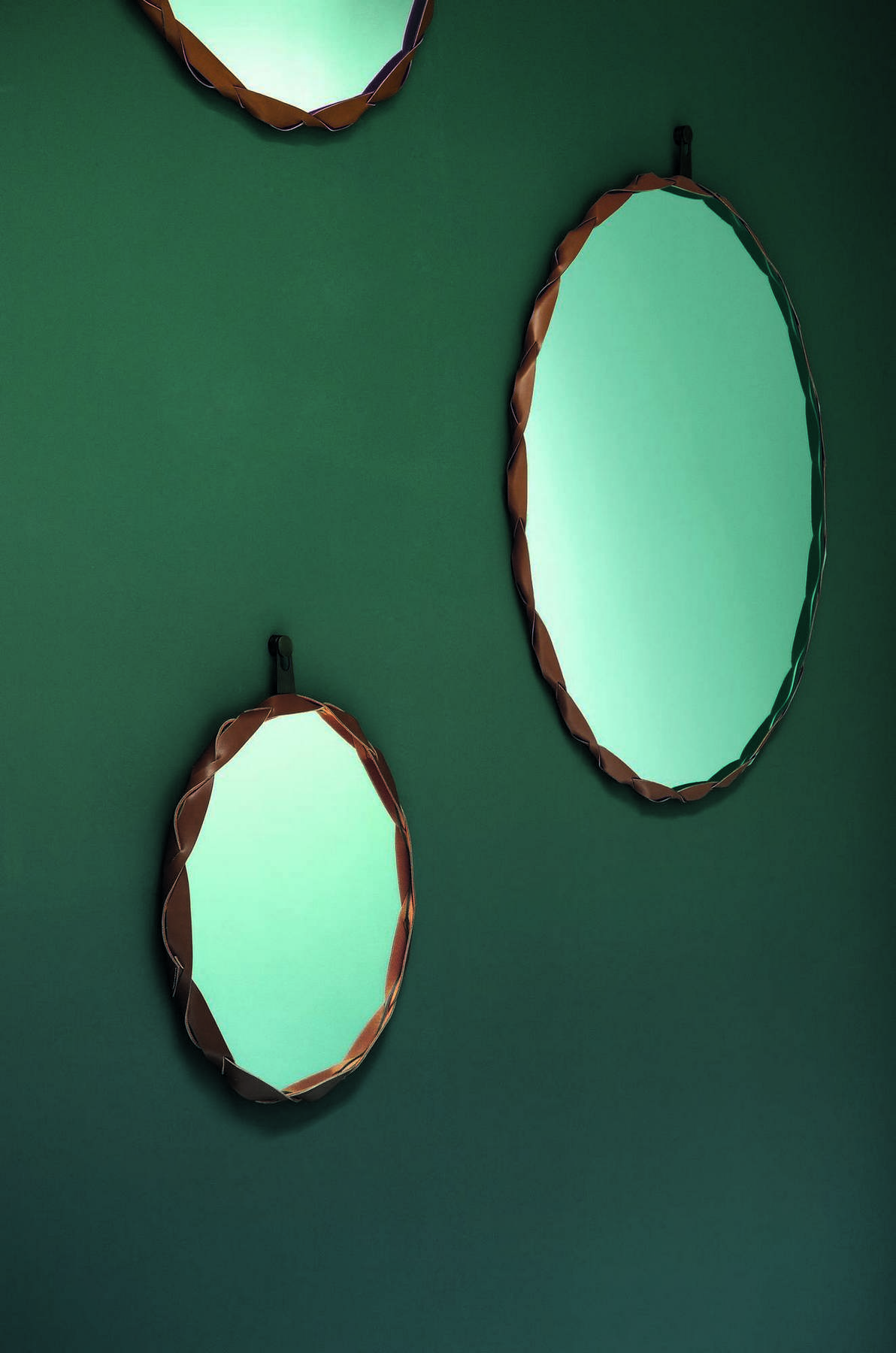 Drei runde Raperonzolo Spiegel von Zanotta mit geflochtenem Lederrahmen an einer grünen Wand.