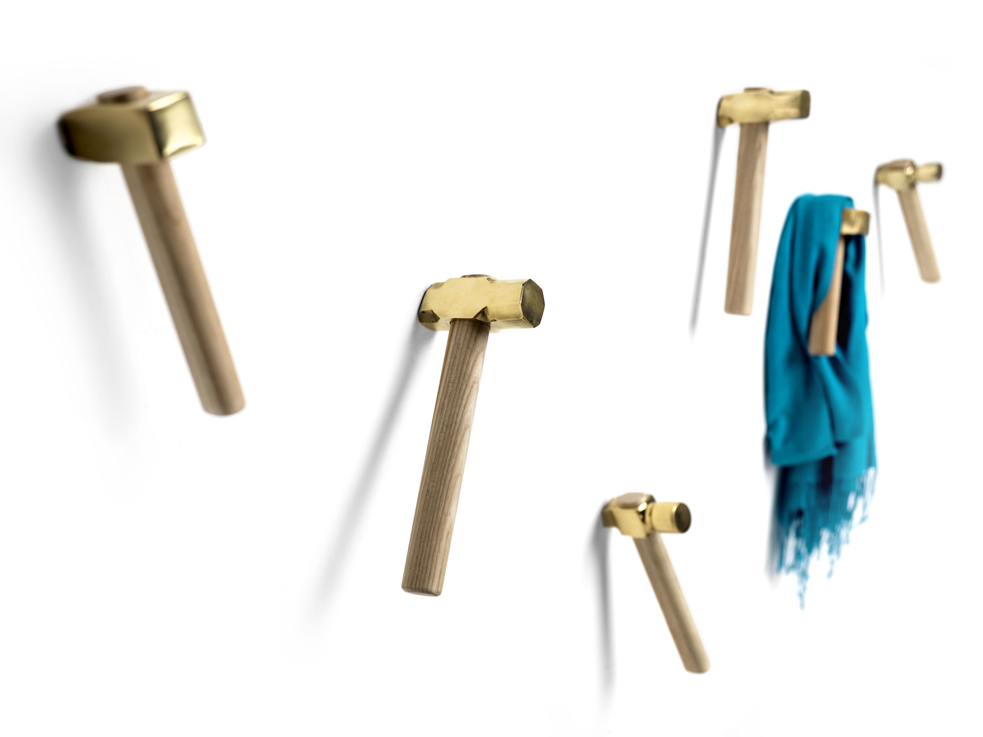 Bastaaa Kleiderhaken: Fünf goldfarbene Hammer-Wandhaken, einer mit blauem Schal, auf weißem Hintergrund. Dekorative Wandgarderobe.