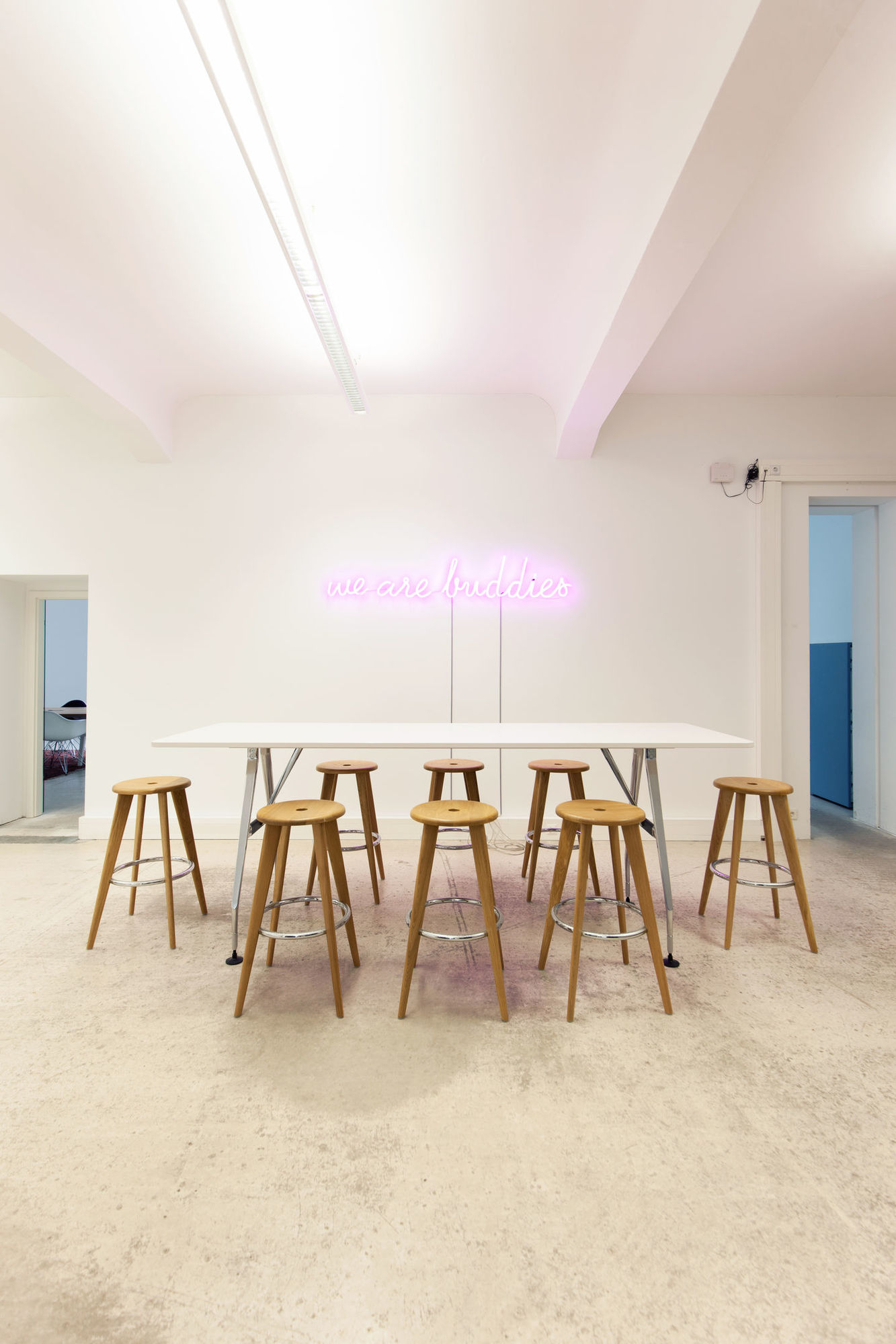 Mehrere Barhocker aus Eiche natur der Marke Vitra an einem Tisch.