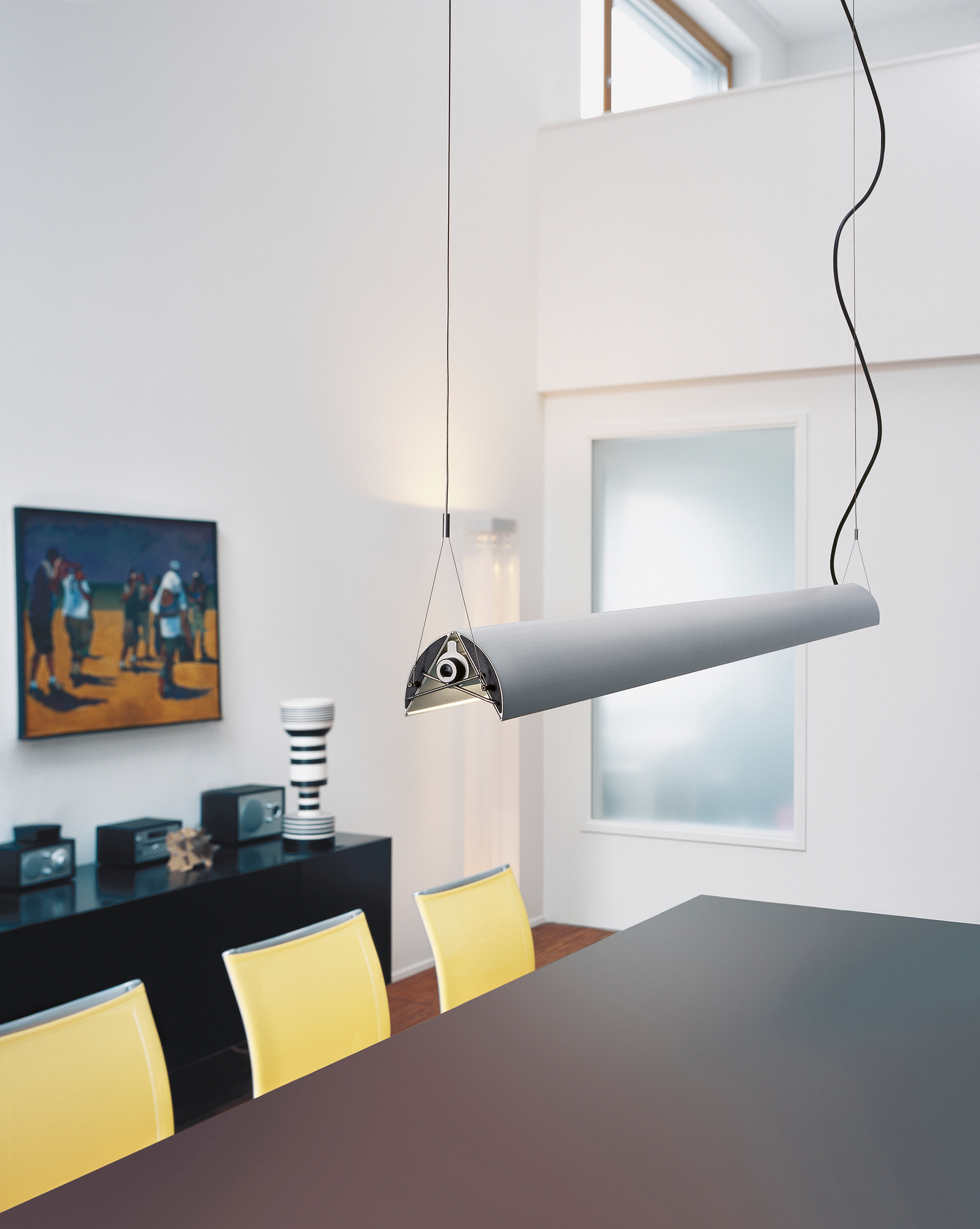 Nahaufnahme der Belux Updown Pendelleuchte aus Aluminium, warmweißes Licht, kabellos dimmbar, über Esstisch.