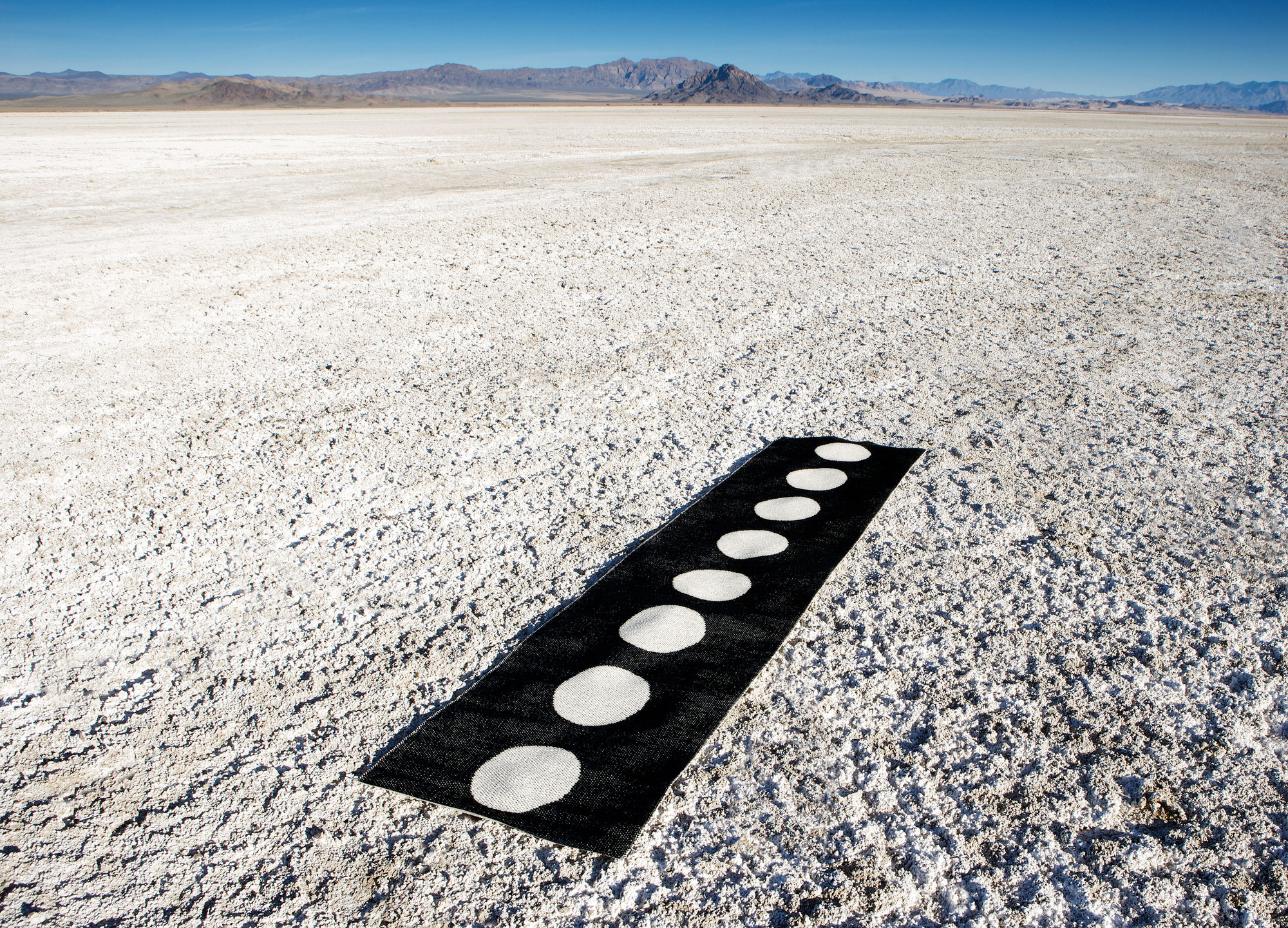 Vera Kunststoffteppich 70x300 cm Pappelina, schwarzer Teppich mit weißen Punkten auf einer weißen Fläche.