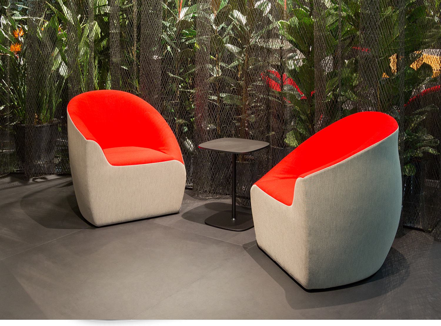 Zwei rote Sessel und ein Lox Table Beistelltisch von Walter Knoll vor Pflanzenwand.