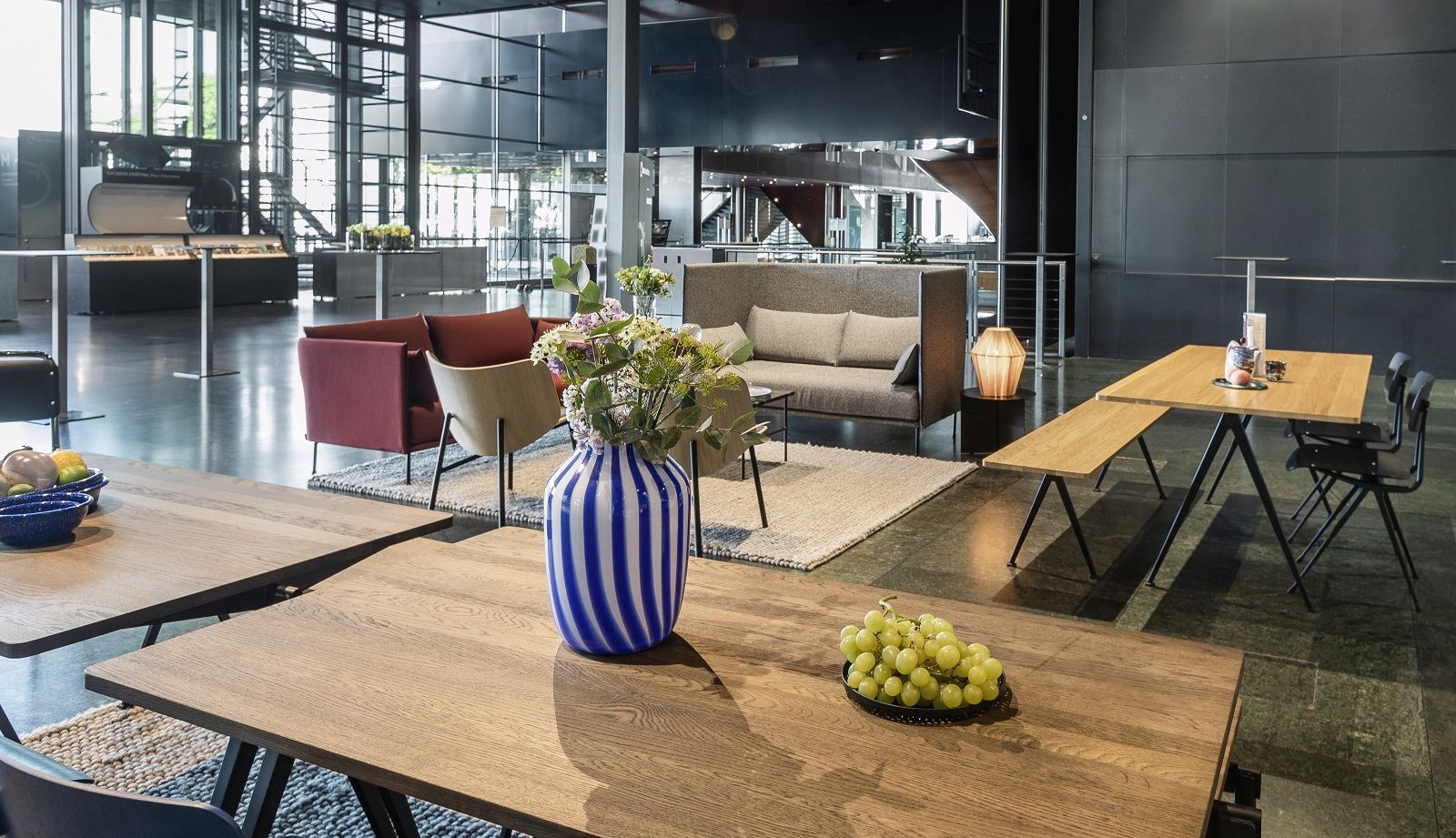 Innenaufnahme mit Hay Silhouette Sofa 2-Sitzer High Back, Tischen, Stühlen und dekorativen Elementen.