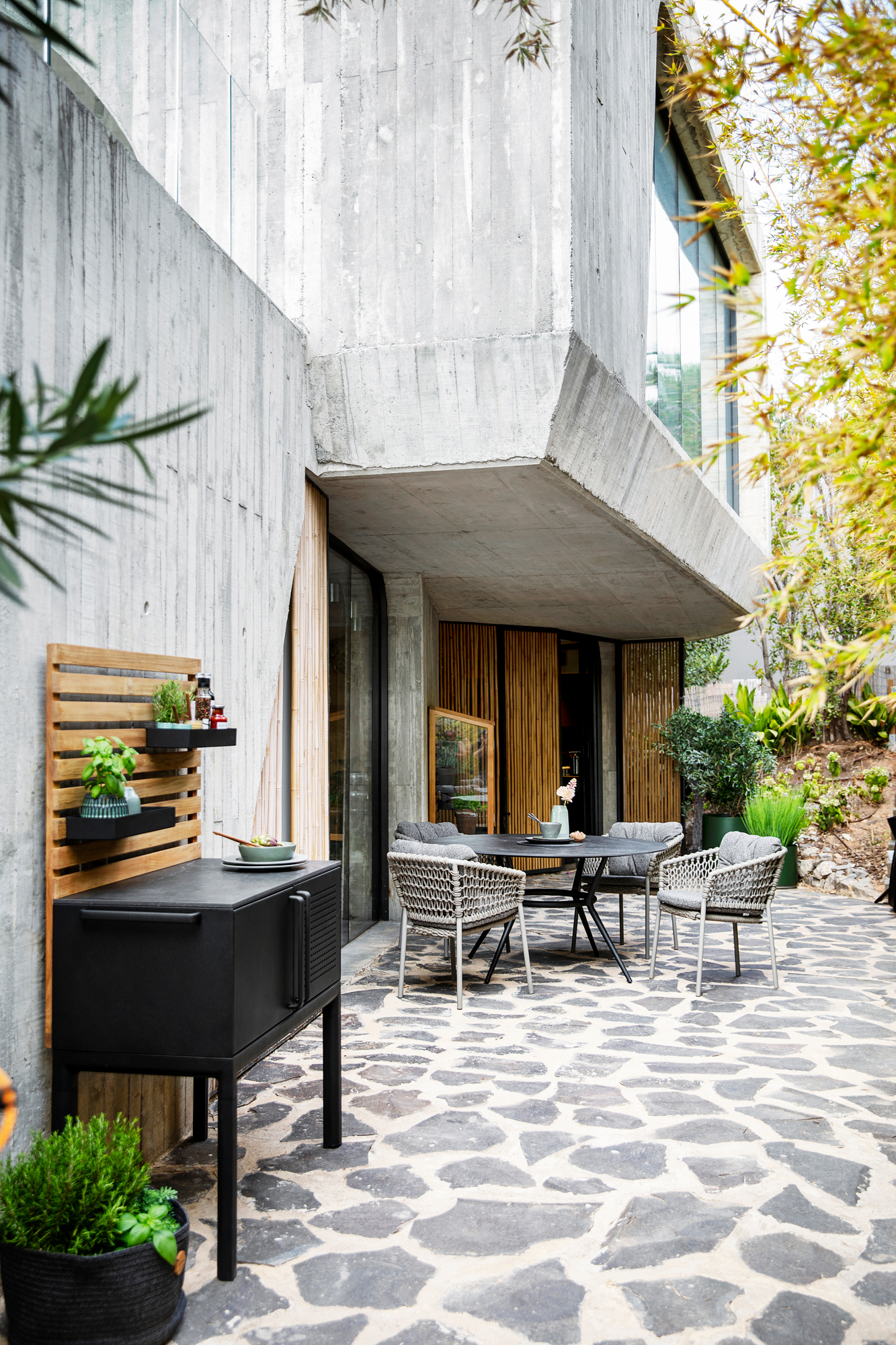 Ocean Outdoor Sessel von Cane-Line auf einer Terrasse mit Tisch und Outdoor-Möbeln.