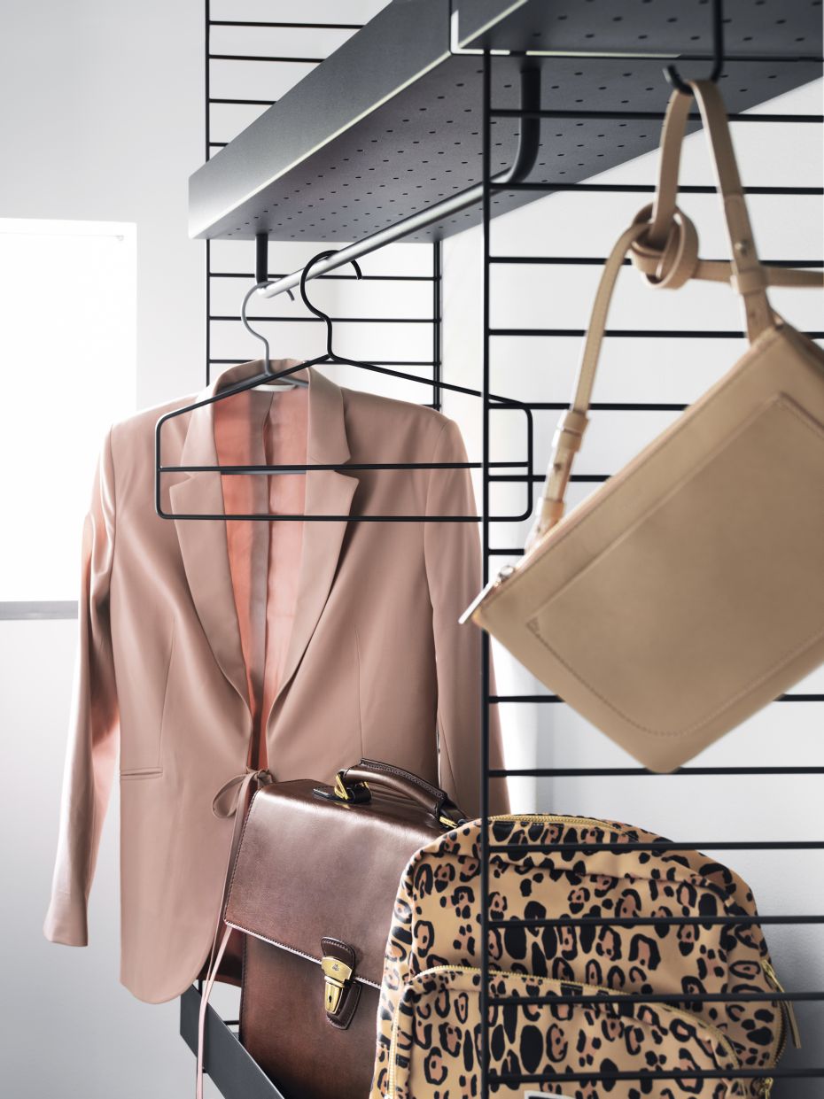 String Furniture Kleiderbügel: Blazer, Aktentasche und Taschen hängen an einem schwarzen Design-Kleiderbügel.