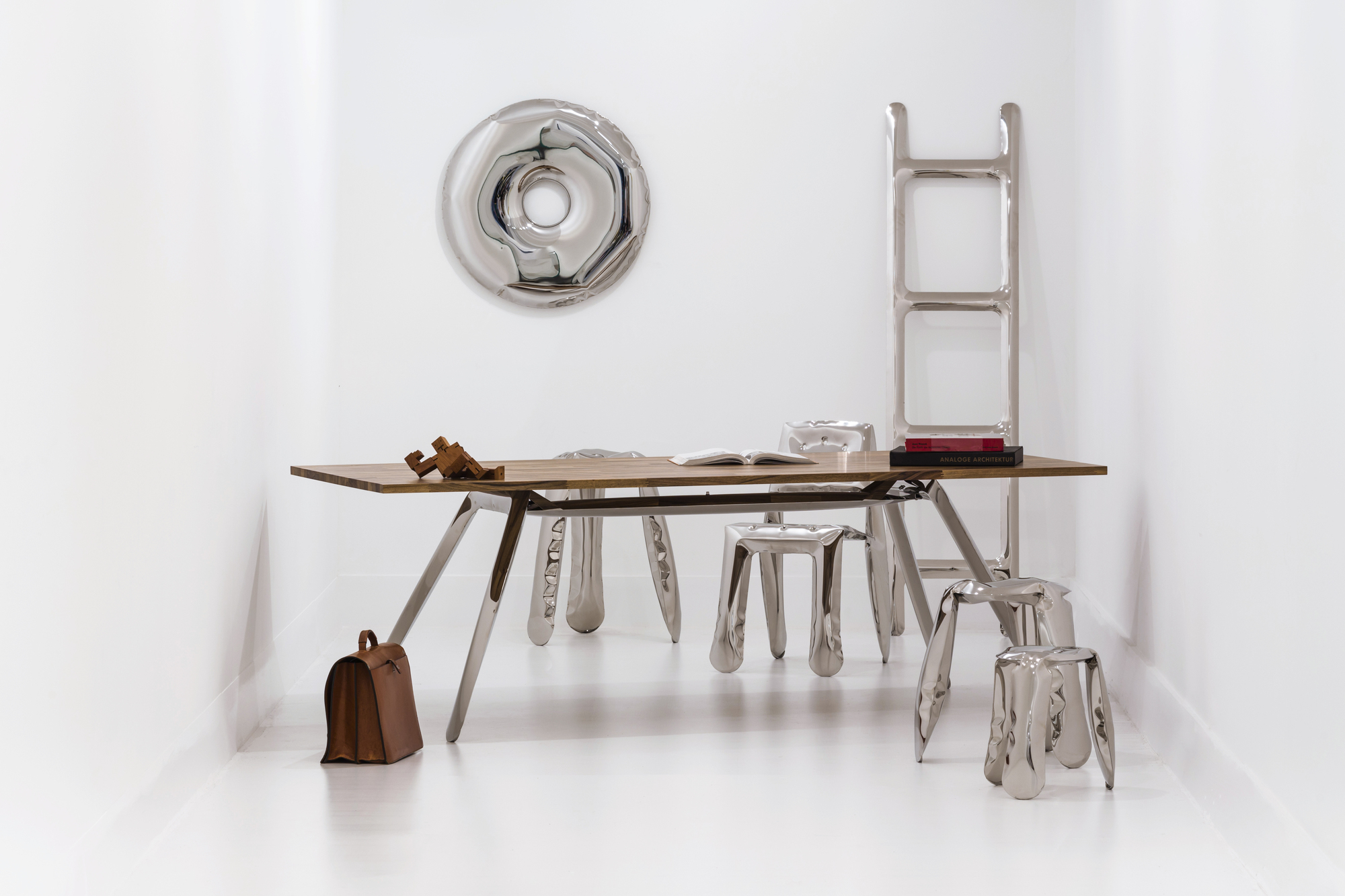 Rondo Spiegel Zieta über einem modernen Schreibtisch mit Stühlen und Leiter aus poliertem Metall.