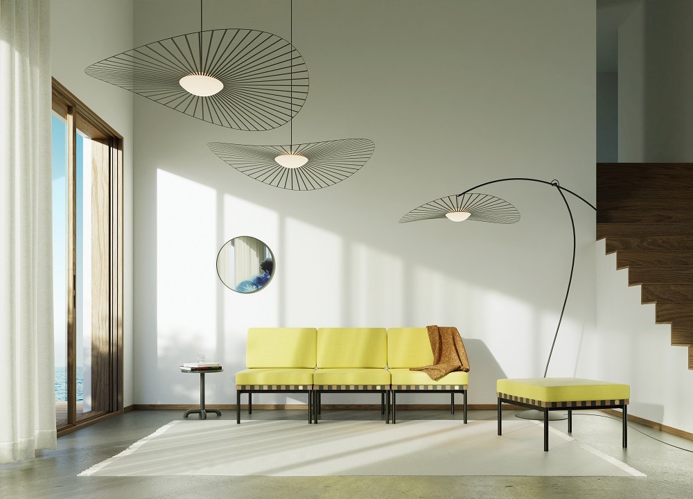 Innenaufnahme mit Vertigo Nova Stehleuchte von Petite Friture in Schwarz und Weiß über gelbem Sofa.