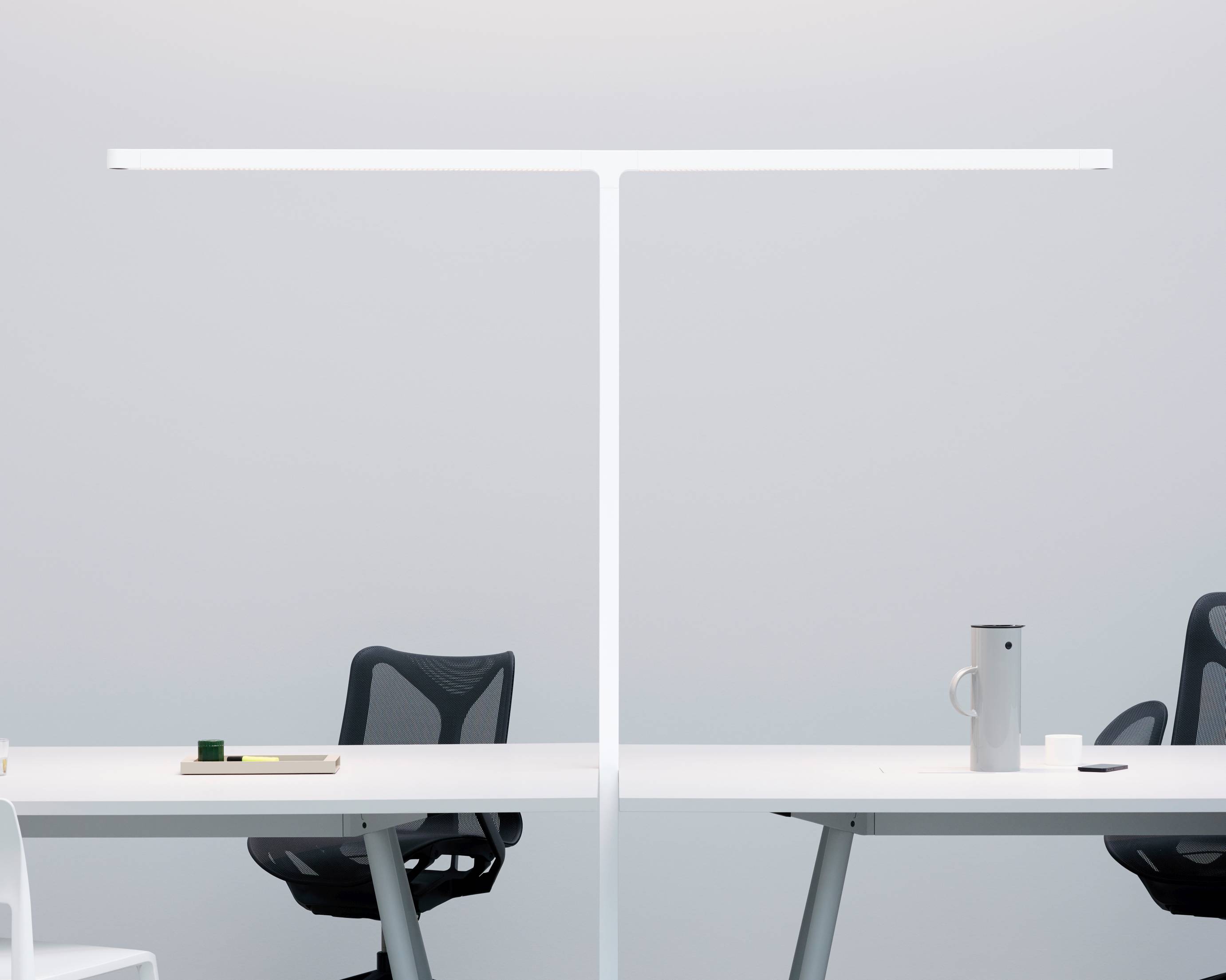 Team Cowork Stehleuchte in Grau über zwei Schreibtische mit Bürostuhl und Accessoires, modernes Büromöbel Design.