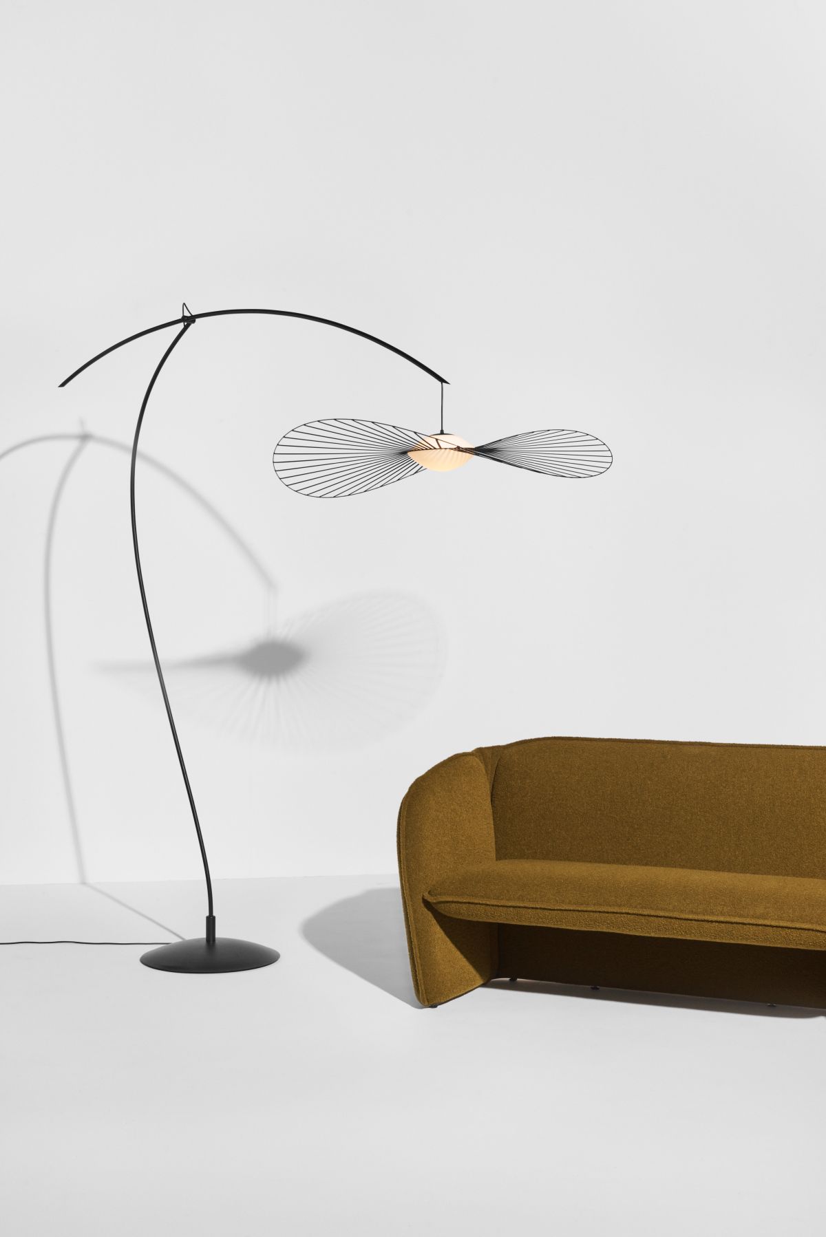 Elegante Bogenlampe mit filigranem Lampenschirm und senfgelbem Sofa für stilvolles Wohnambiente. Moderne Stehlampe für Wohnzimmer.