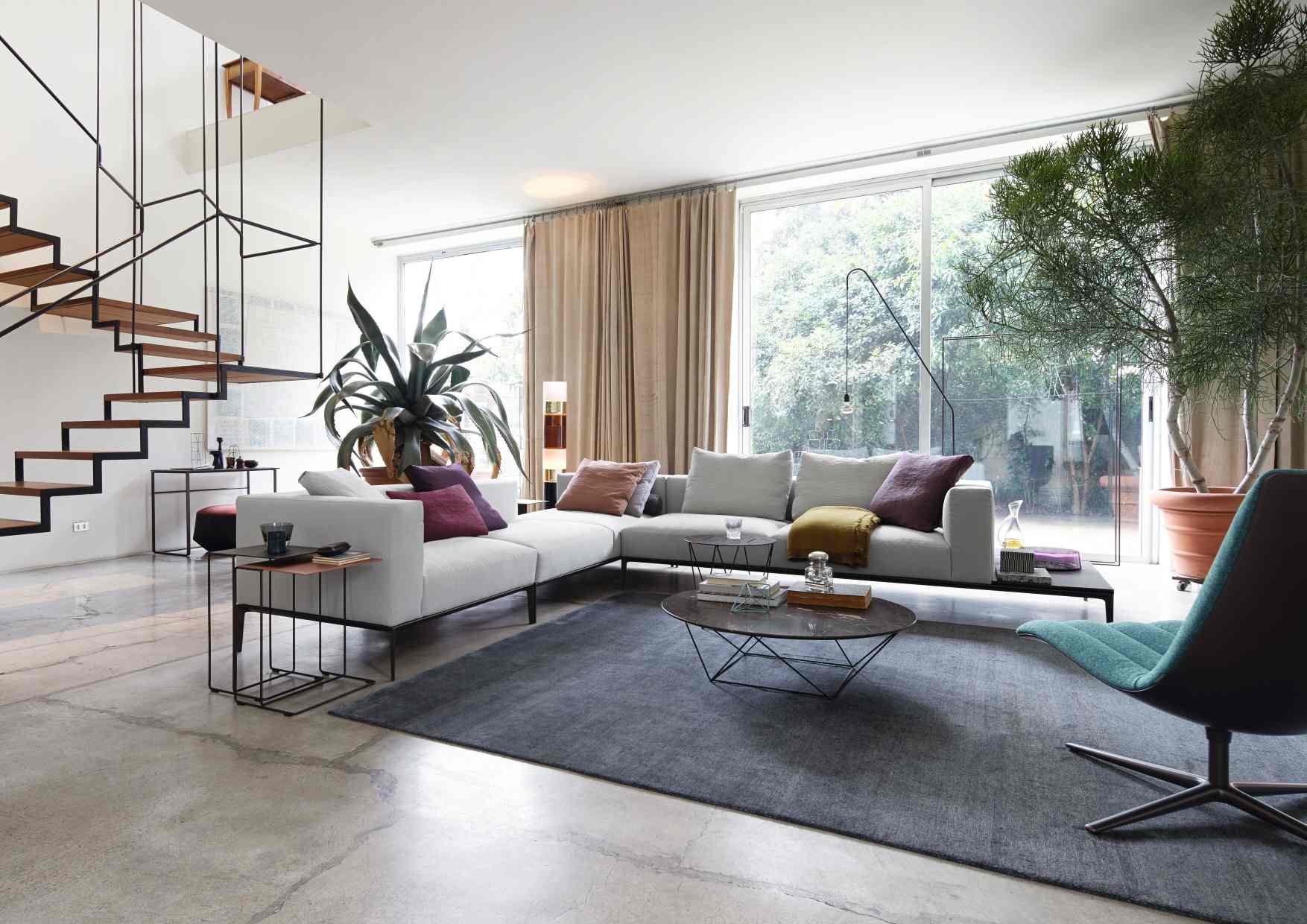 Helles Wohnzimmer mit Walter Knoll Sofa, Teppich, Tisch und Treppe.