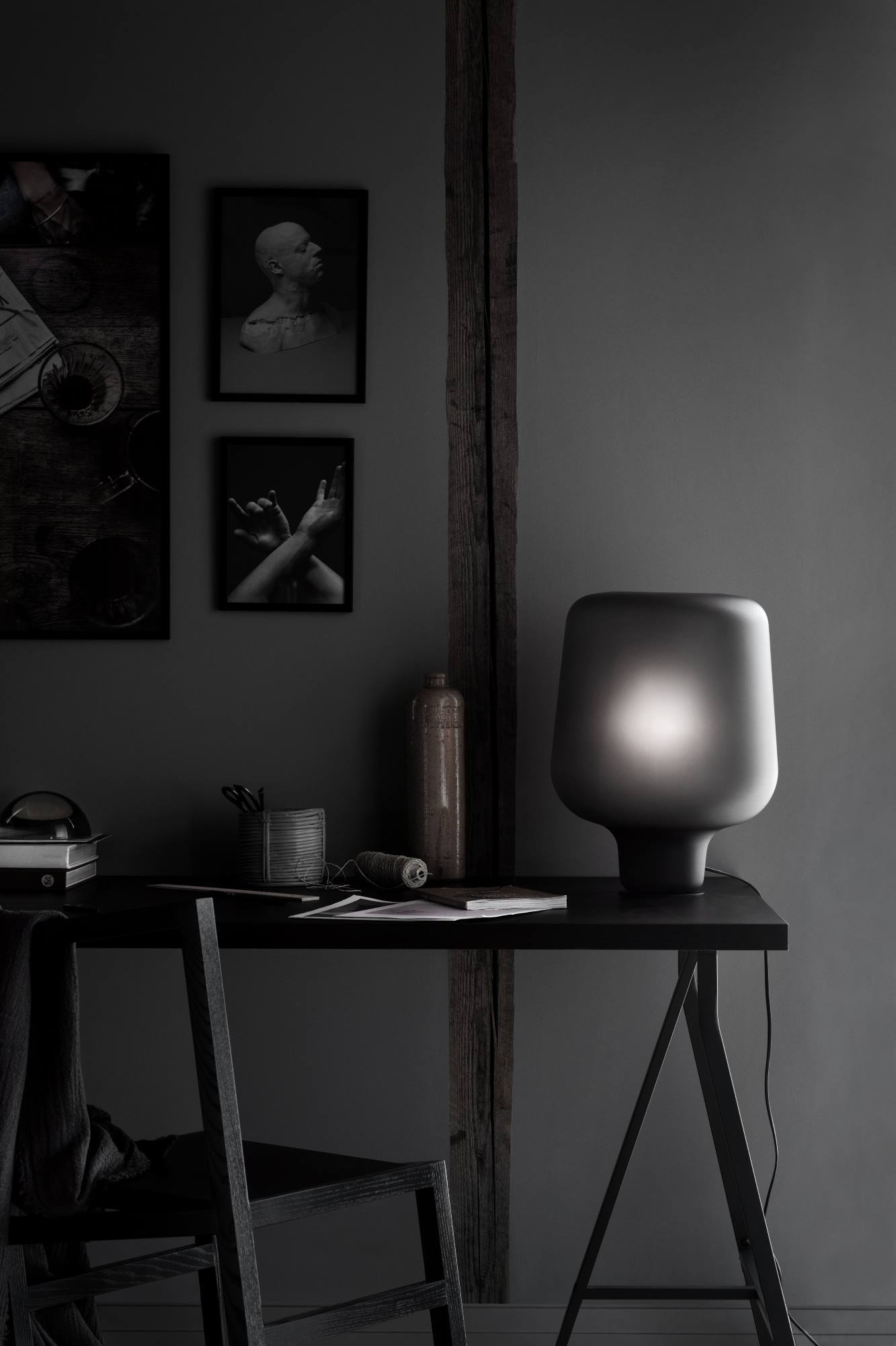 Mattgraue "Say My Name" Tischleuchte von Northern auf dunklem Schreibtisch, stimmungsvolle Beleuchtung im modernen Arbeitszimmer.