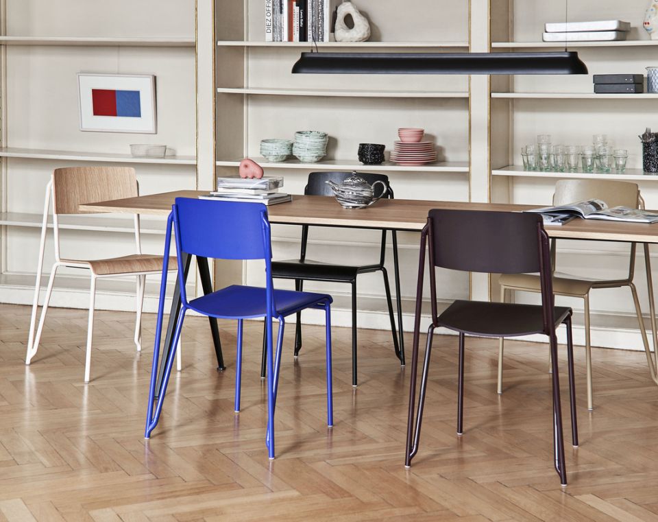Mehrere Hay Petit Standard Stühle in verschiedenen Farben um einen Holztisch in einem Esszimmer.