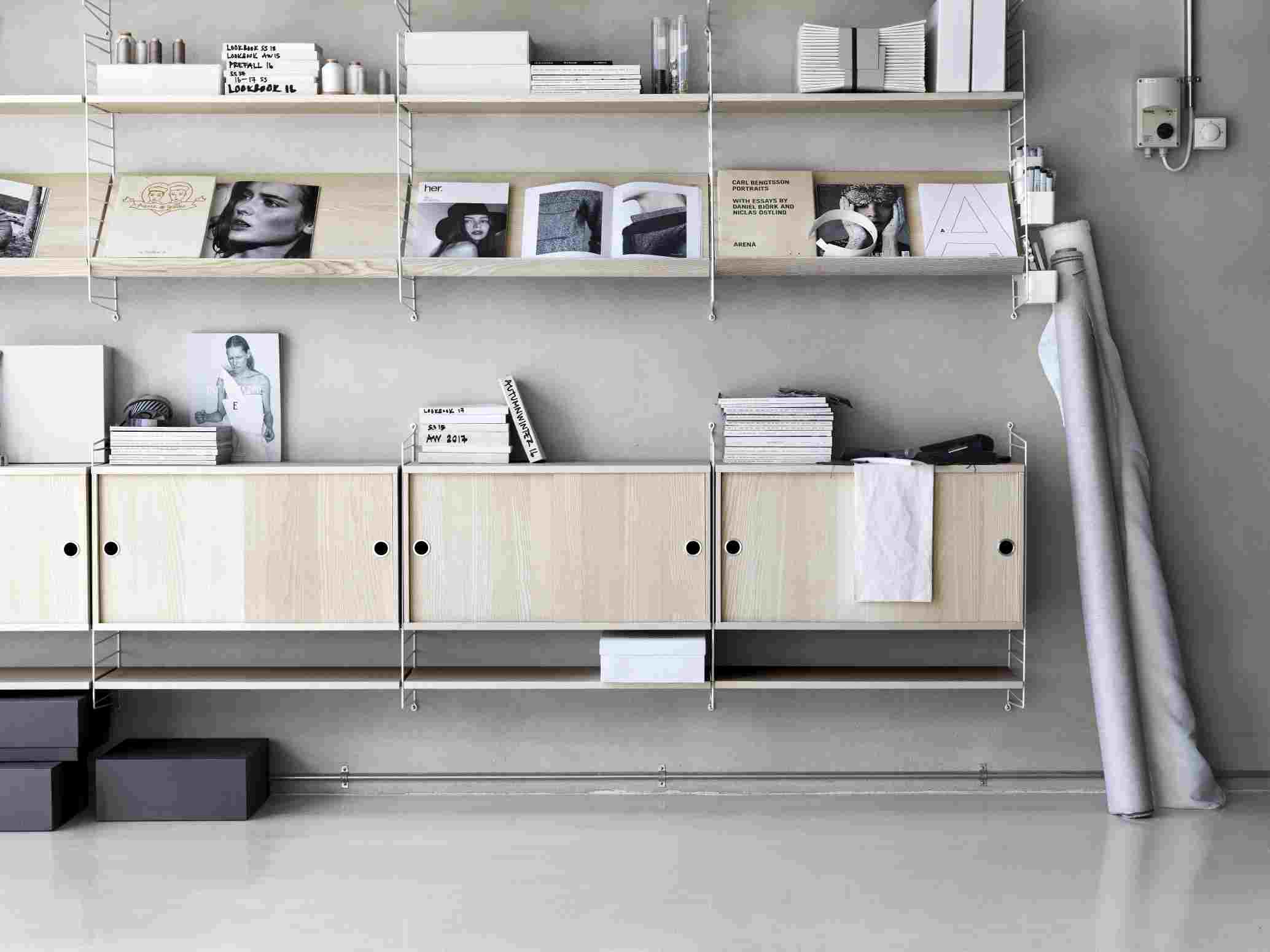 String Regalsystem mit Holzablagen und Schränken an grauer Wand, modernes Wohnzimmer Design.