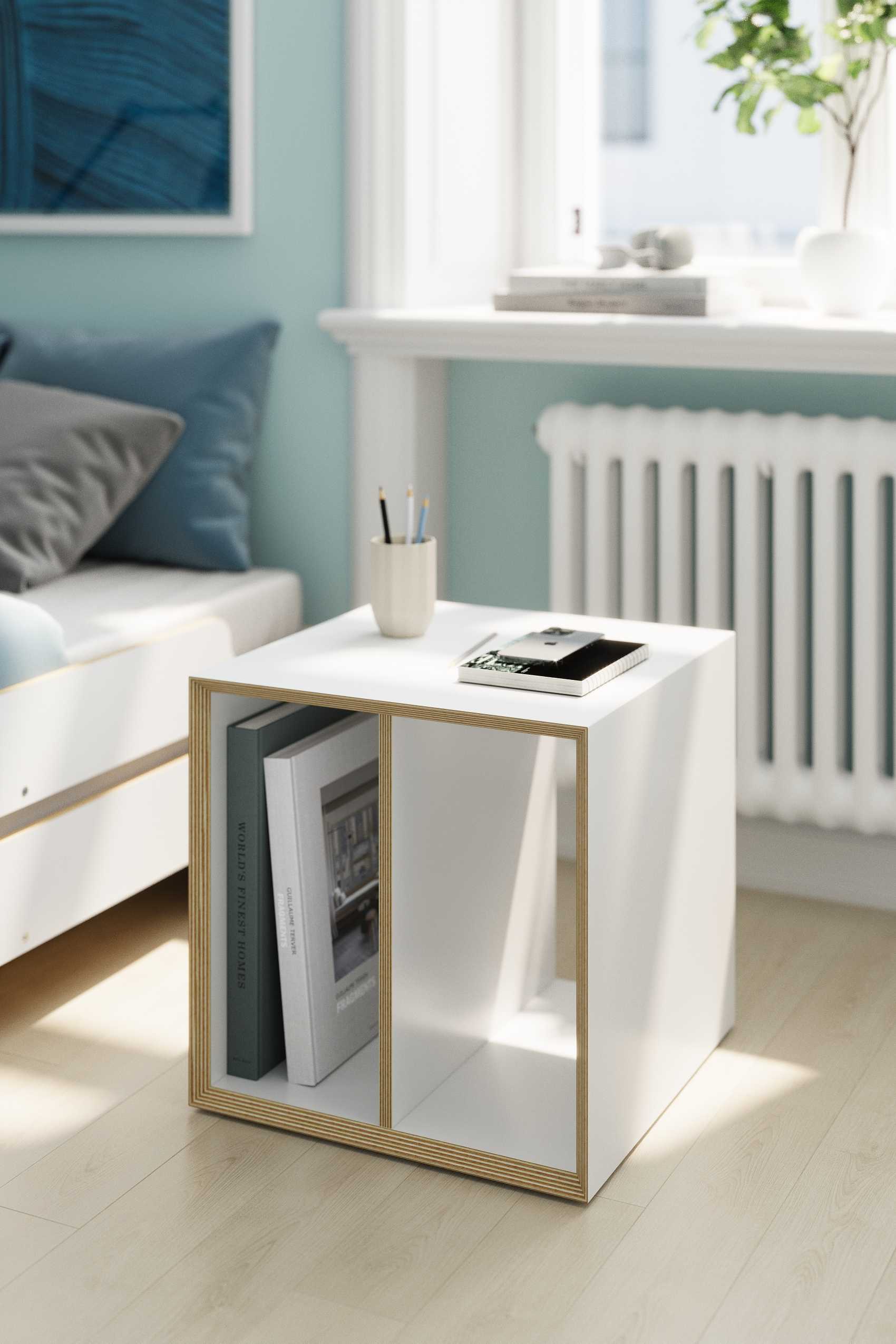 Weißer Vertiko Dice Beistelltisch von Müller Möbelwerkstätten mit Büchern als Nachttisch im Schlafzimmer.