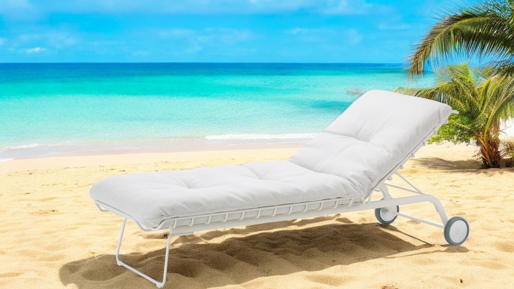 Weiße Leyasol Sonnenliege von Freifrau Manufaktur am Strand mit Meer und Palmen im Hintergrund.