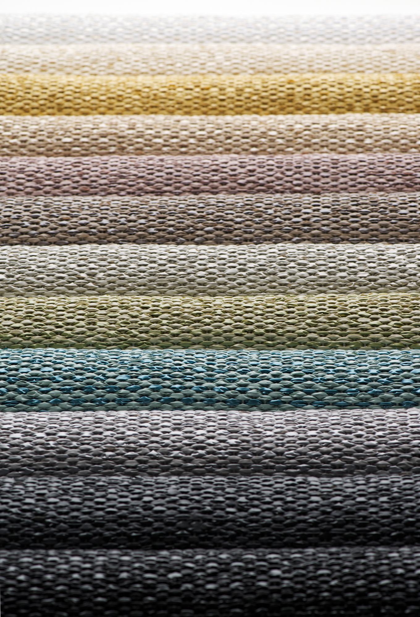 Detailaufnahme verschiedener Farbvarianten des Svea Kunststoffteppichs von Pappelina. Teppichmuster in Schlamm- und Erdtönen.