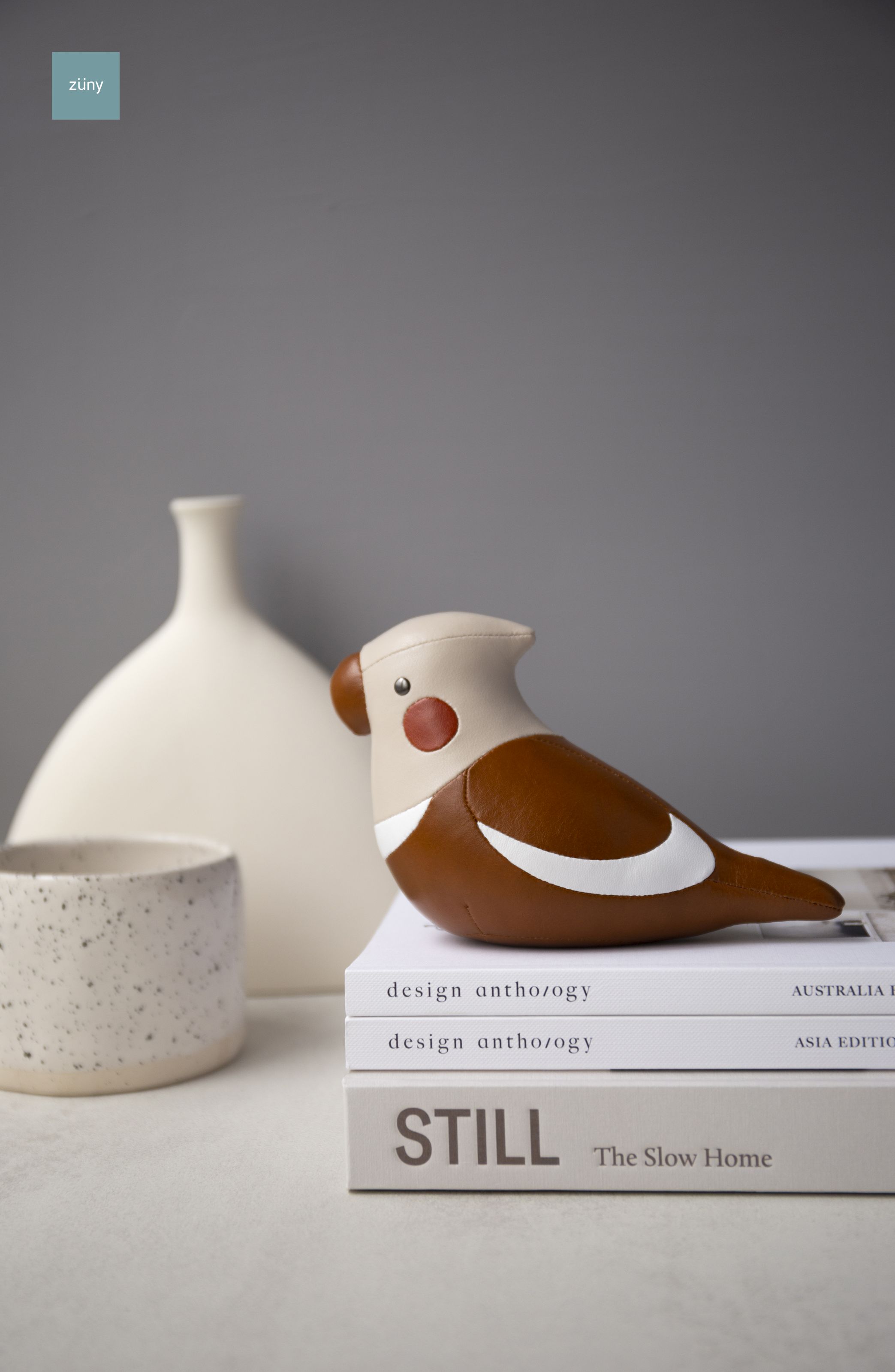 Züny Nymphensittich Briefbeschwerer in Tan und Weizen auf Bücherstapel, dekoratives Wohnaccessoire.