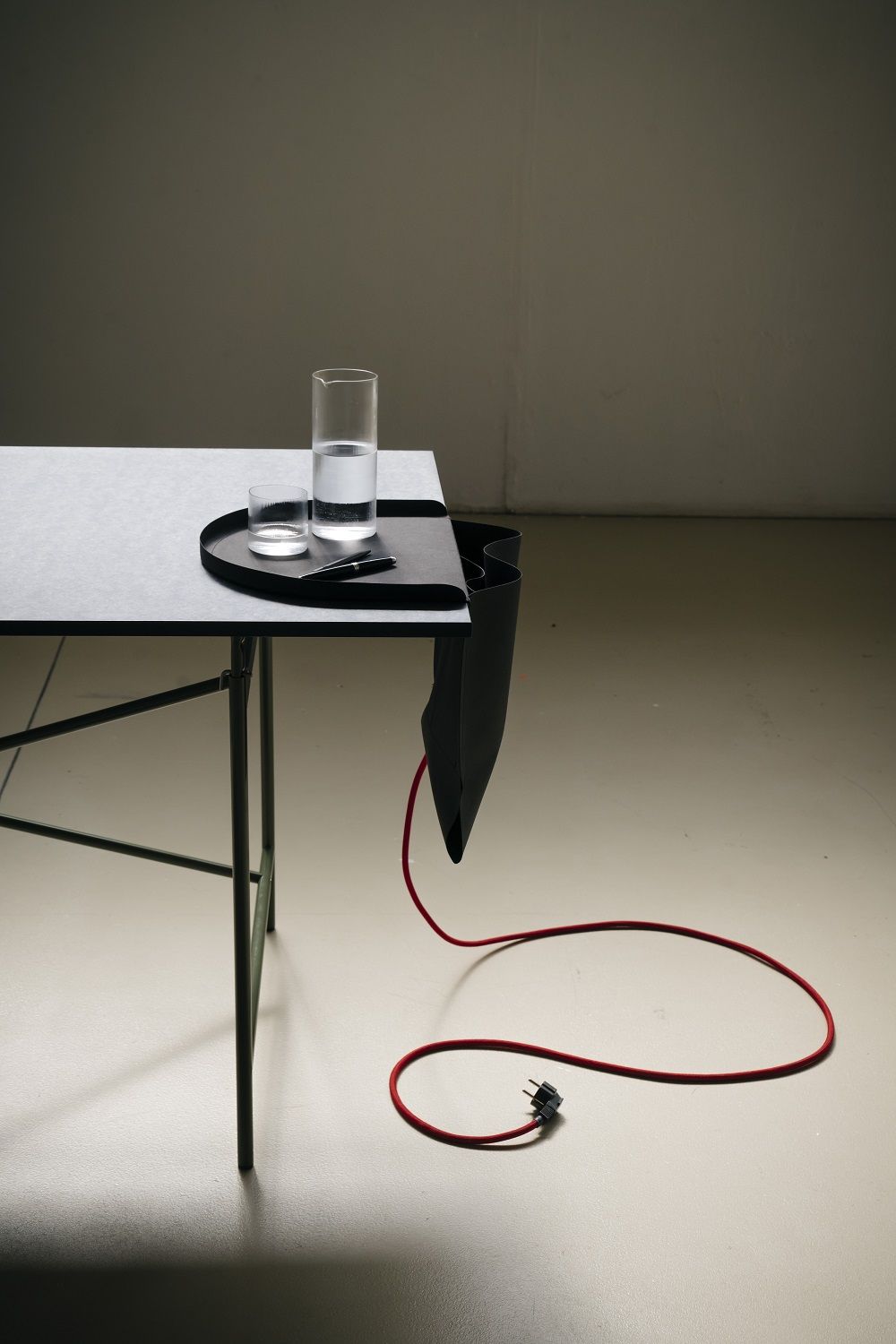 Salto Papiermöbel von Richard Lampert: Schreibtisch mit Organizer, Glas Wasser, Stift und rotem Kabel.