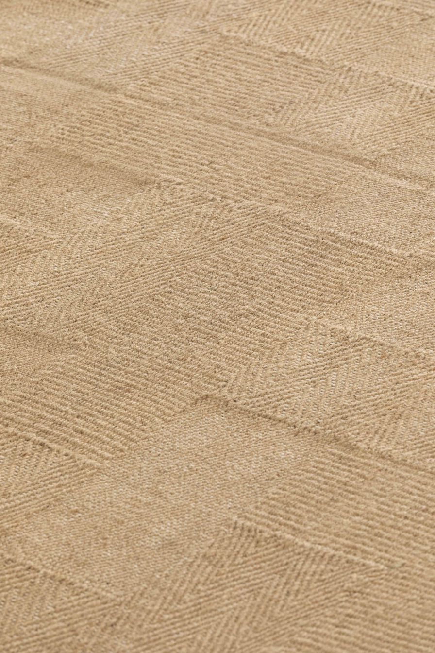 Detailaufnahme des beigen Roots Teppichs von Gan mit Fischgrätenmuster, ideal für Wohnzimmer.