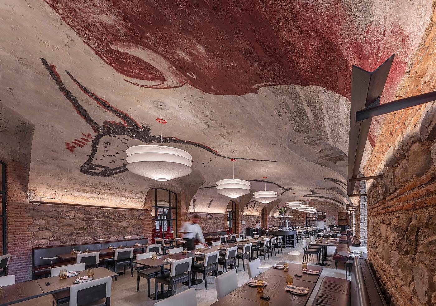 Innenansicht eines Restaurants mit Ingo Maurer Pendelleuchten, die von der Decke hängen.