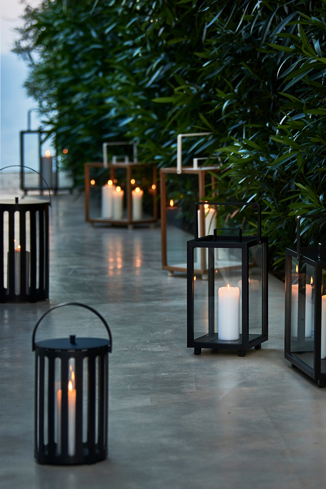 Mehrere Cane-Line Lighthouse Laternen aus Aluminium mit brennenden Kerzen im Außenbereich.