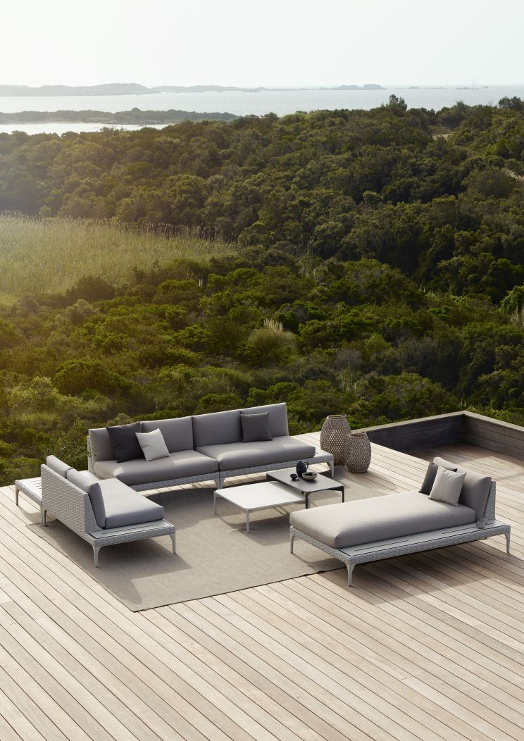 Bild eines grauen Dedon Gartenmöbel-Sets mit Izon Beistelltisch auf einer Holzterrasse mit Blick auf die Natur.