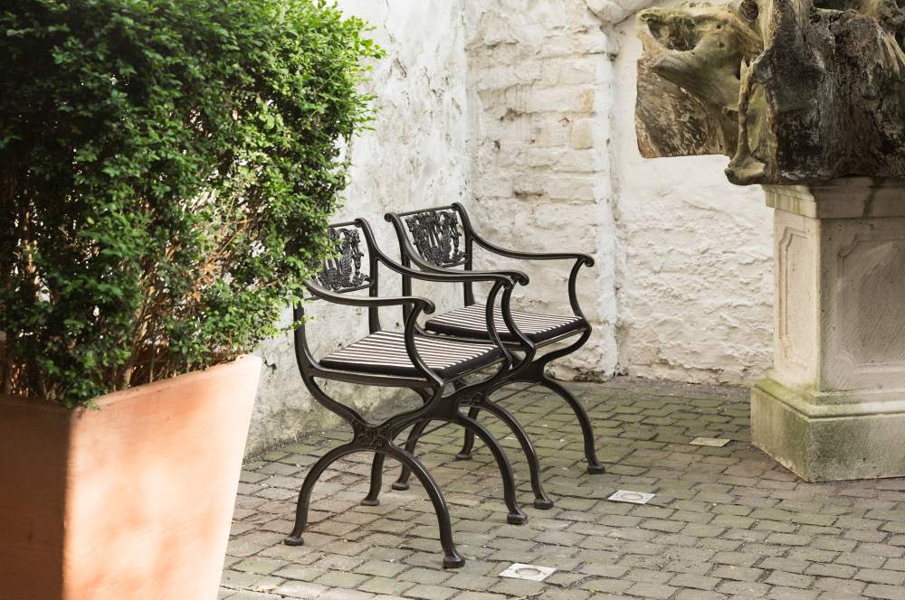 Zwei schwarze Tecta Gartensessel mit gestreiften Kissen auf einer Terrasse im Freien.