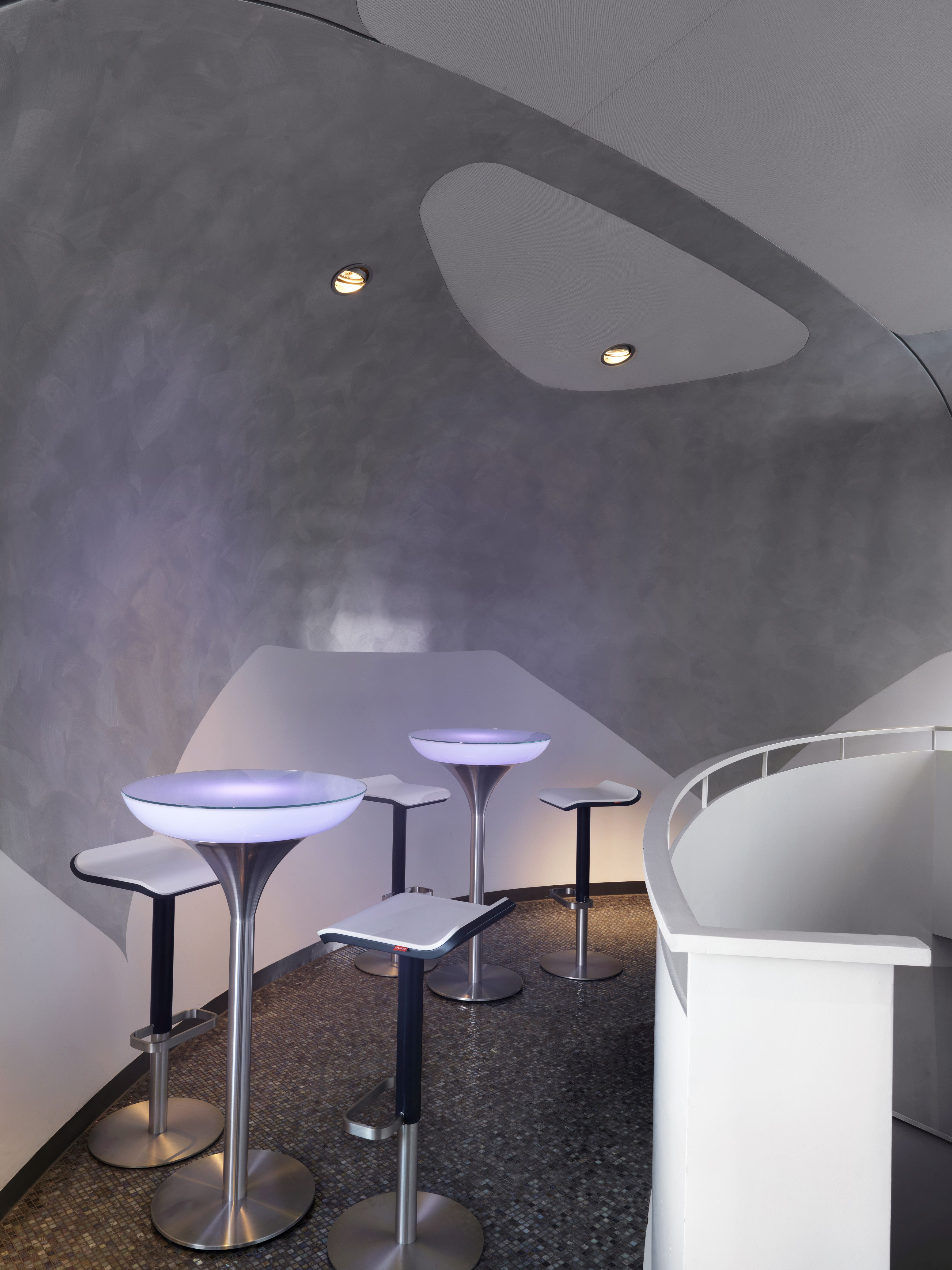 Mehrere höhenverstellbare ED Barhocker von Moree in modernem Ambiente mit Bar-Tischen und Beleuchtung.